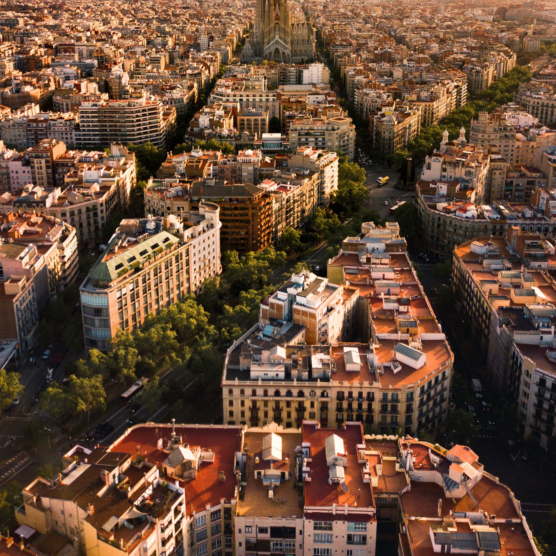 Uitzicht over de zonnige straten van Barcelona met in de verte de Sagrada Familia en de Middellandse Zee. 