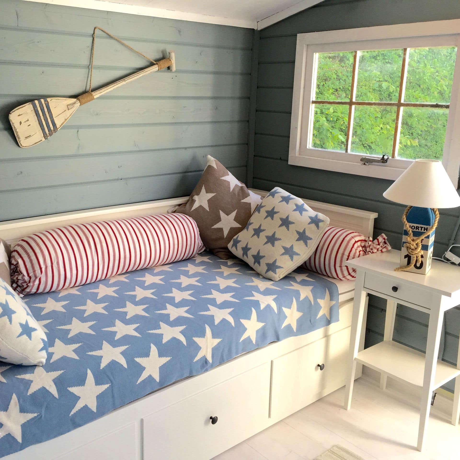 Interieur van een blauw, houten strandhuisje met een houten bank