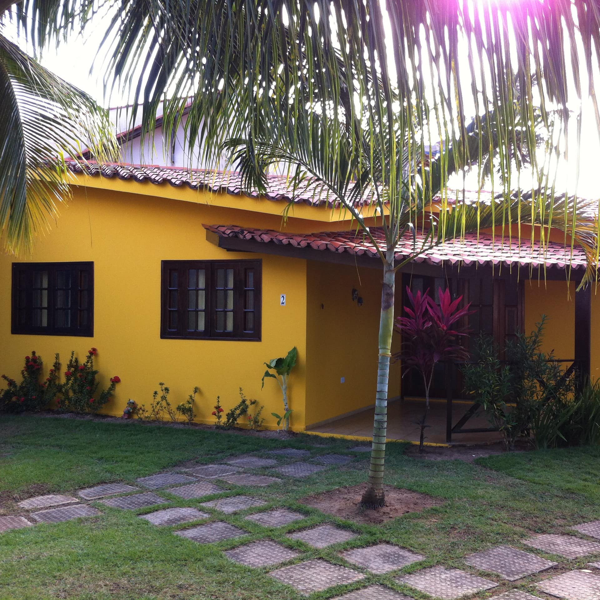 Chalé amarelo com janelas de madeira, com jardim e caminho de pedras