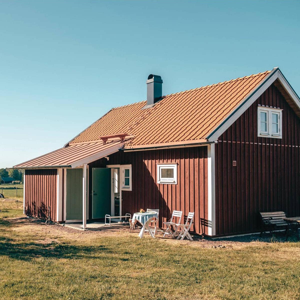 Rött fritidshus med vita knutar och uteplats