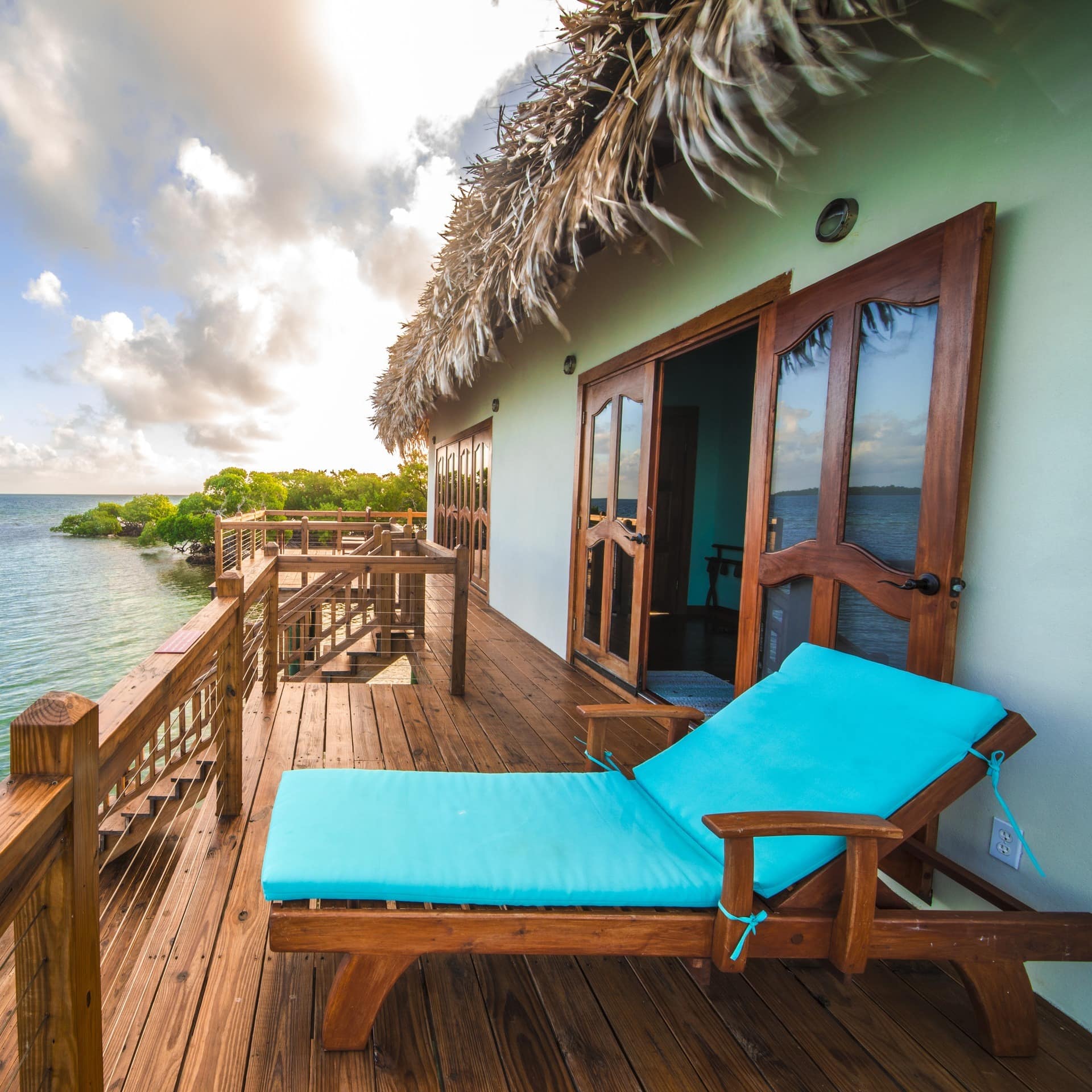 An over-water villa in Belize with a wooden deck and steps into the sea