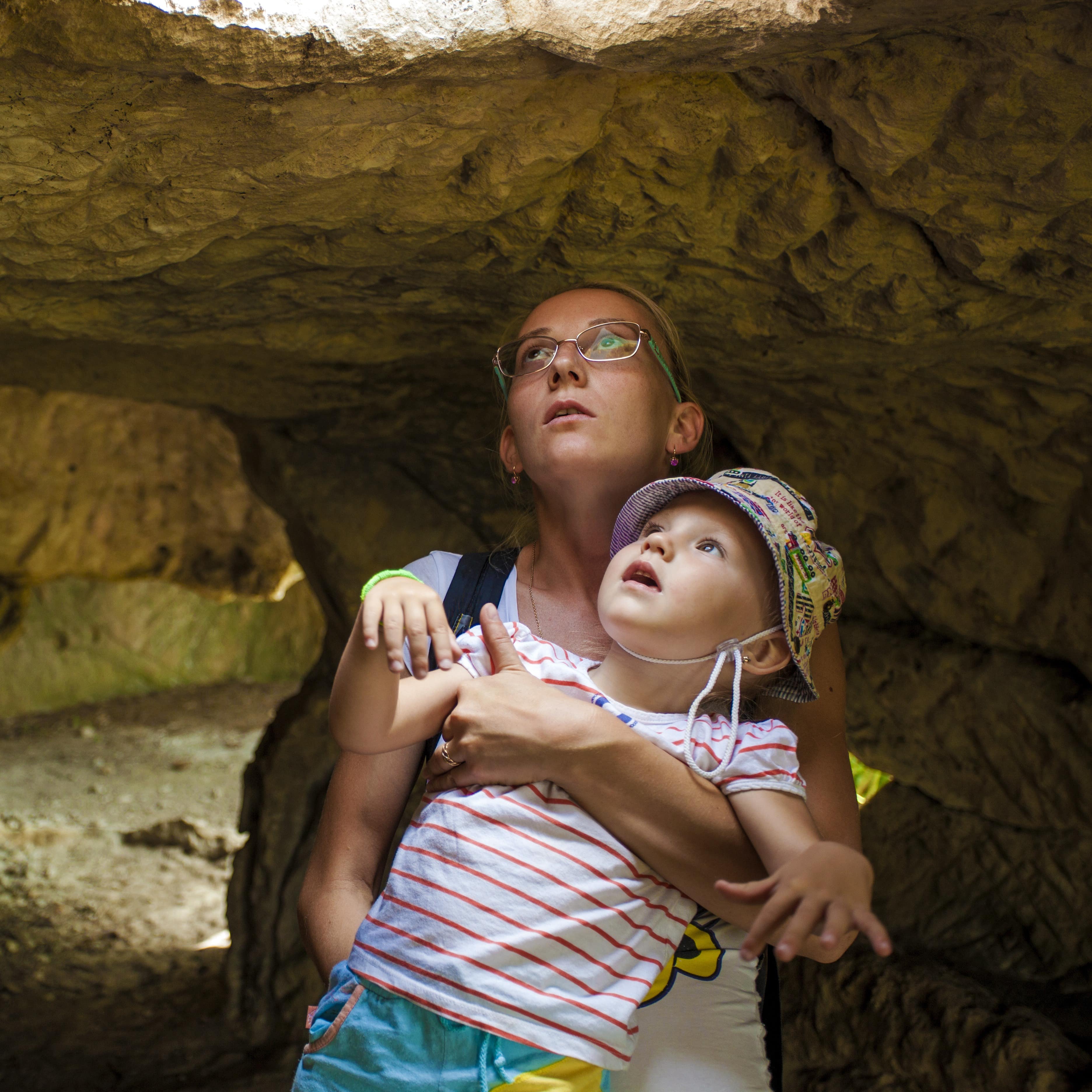 Amother and daughter in the cave looking up at light