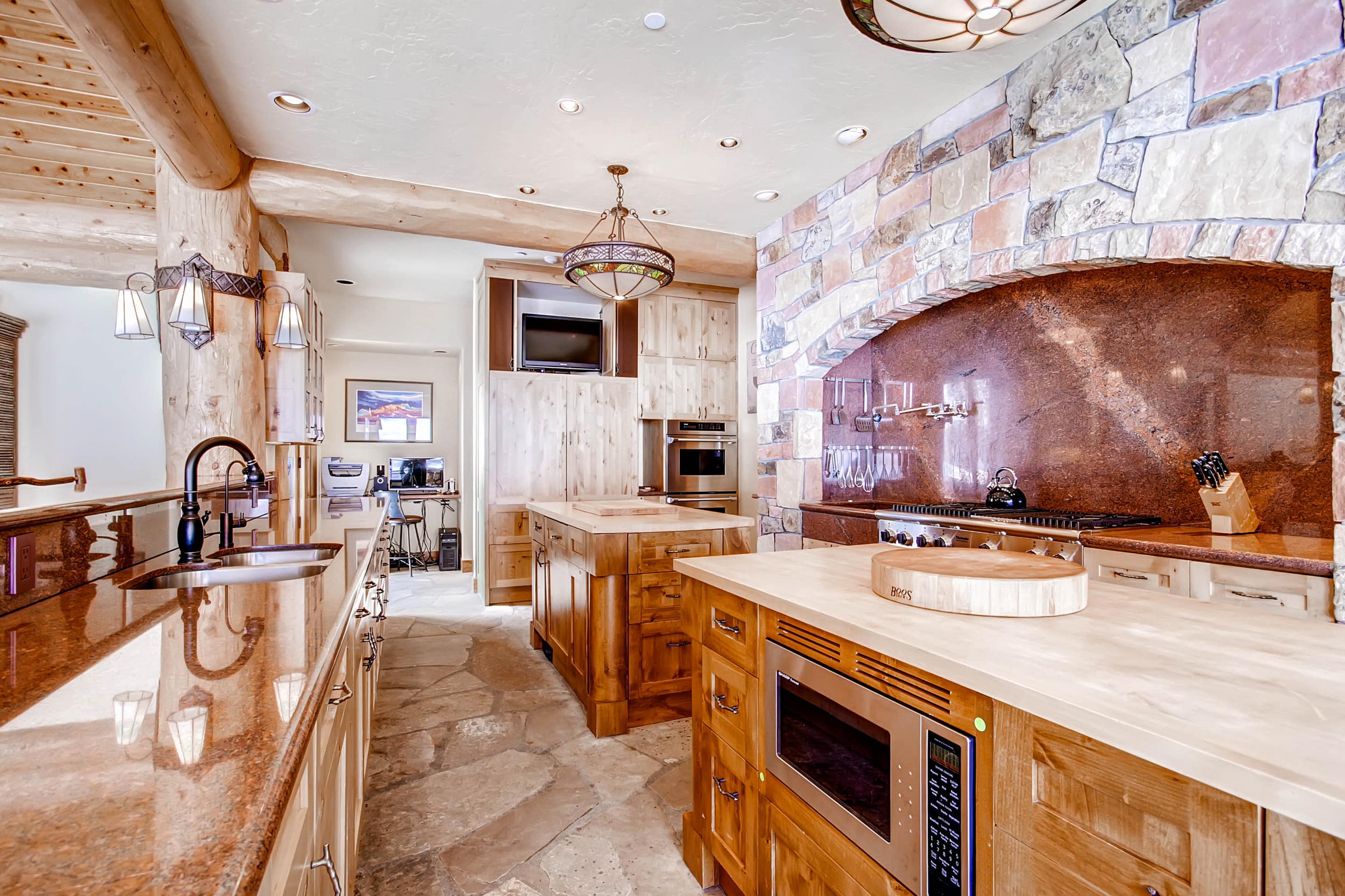 This is a kitchen with two islands and stone-based decor.