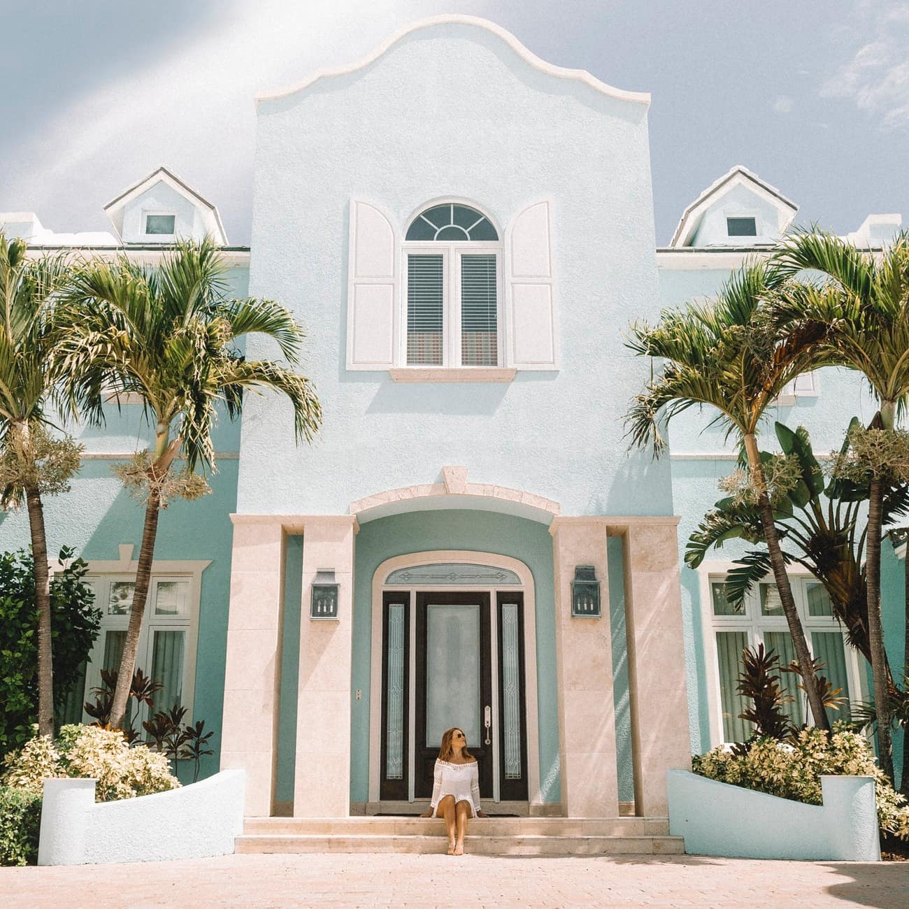 A light-blue mansion fronted with palm trees