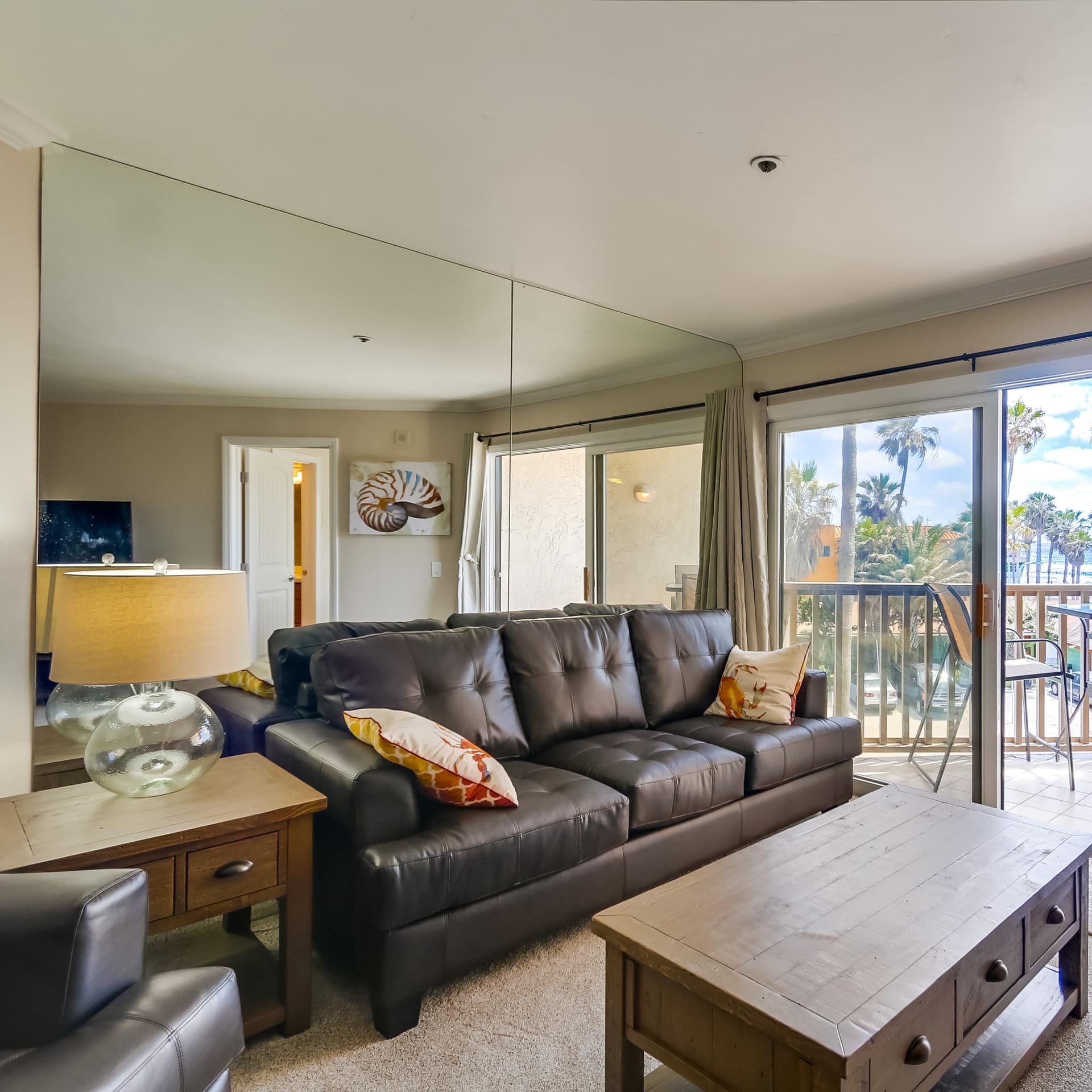 The living area and balcony of a beachfront condo, overlooking the water
