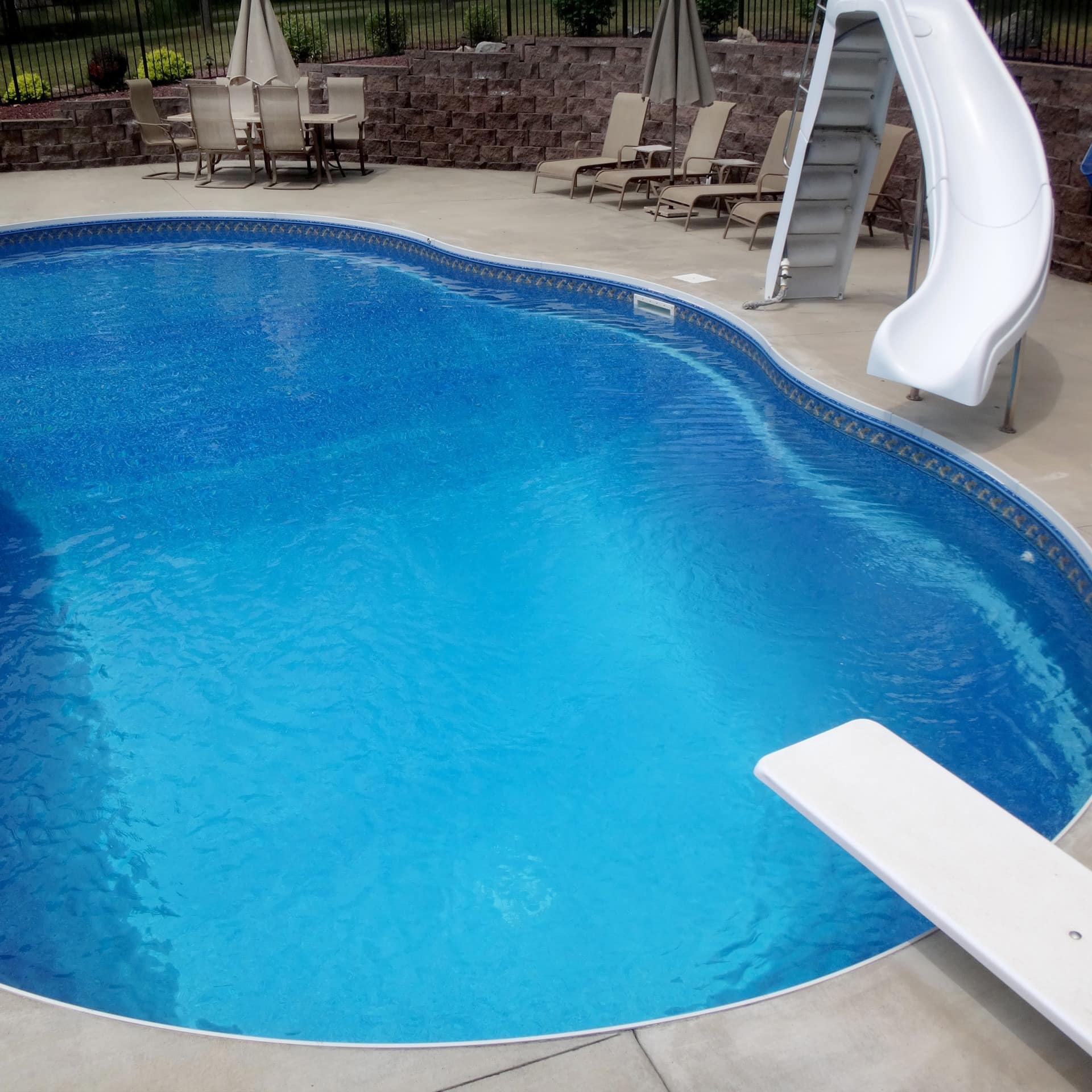 A luxury vacation home rental's outdoor pool with a diving board and a slide
