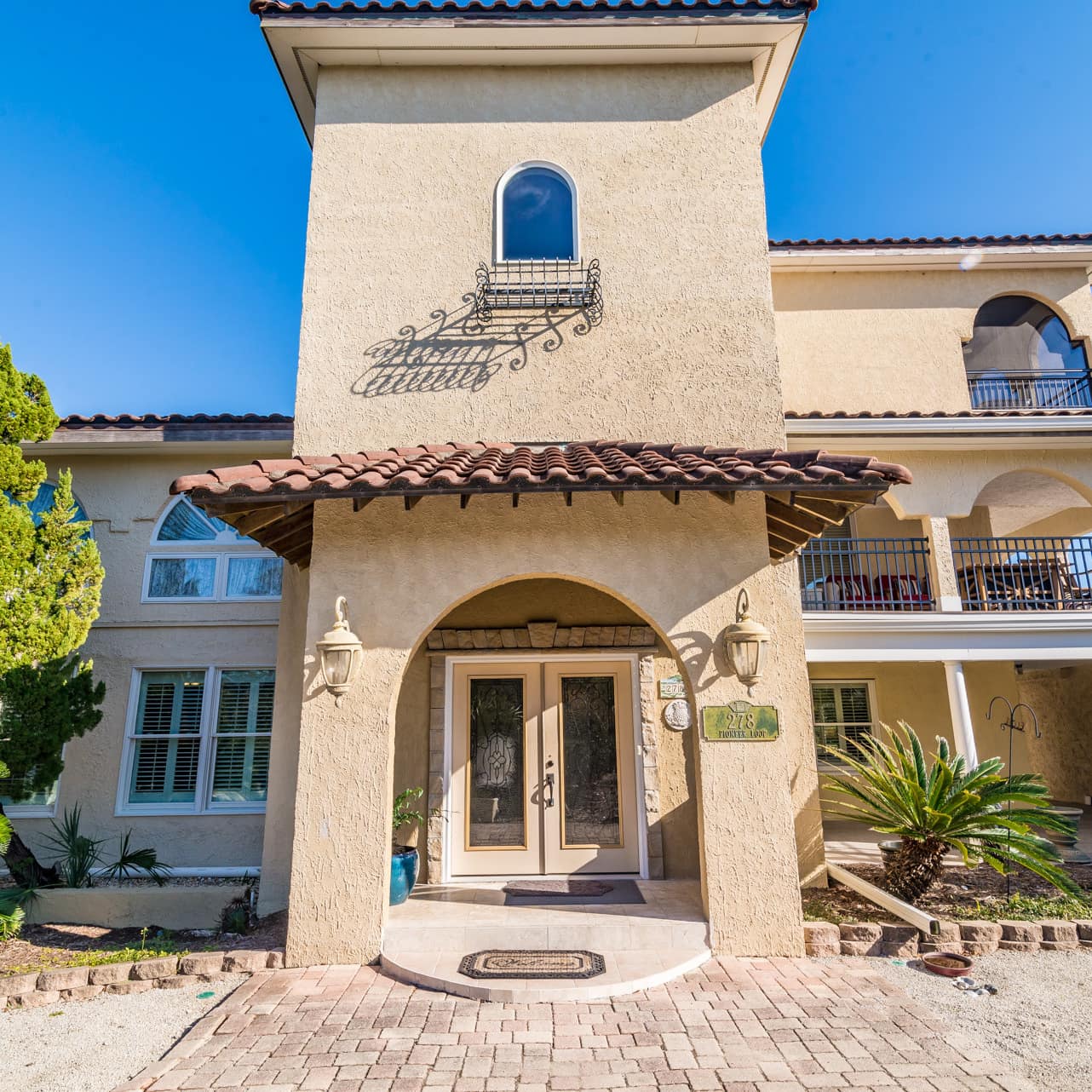 A stucco-finished home in the Spanish style with a shaded porch and colonnaded al fresco balconies