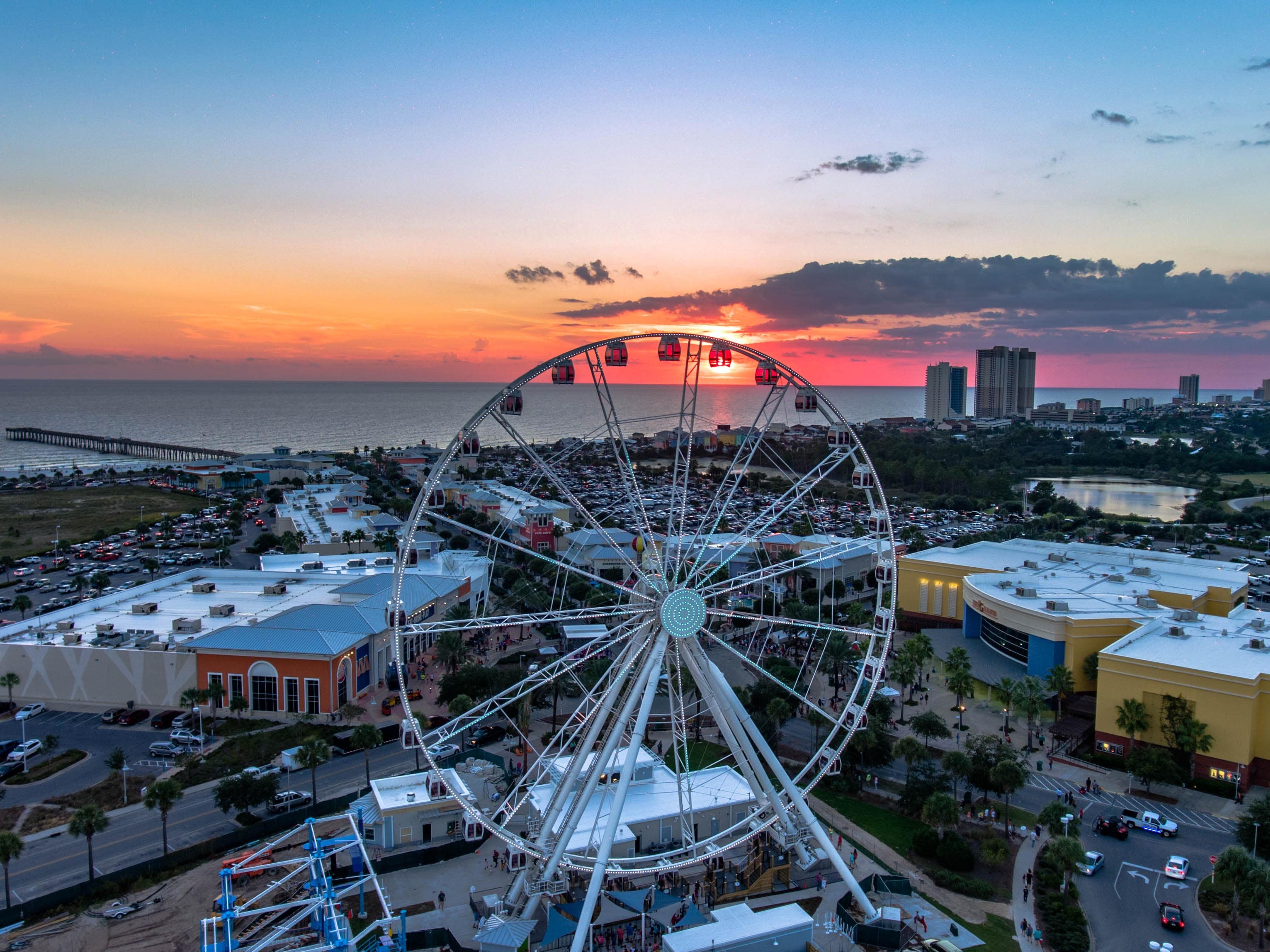 picture of the skywheel at pier park in panama city beach, with a sunset over the water in the background