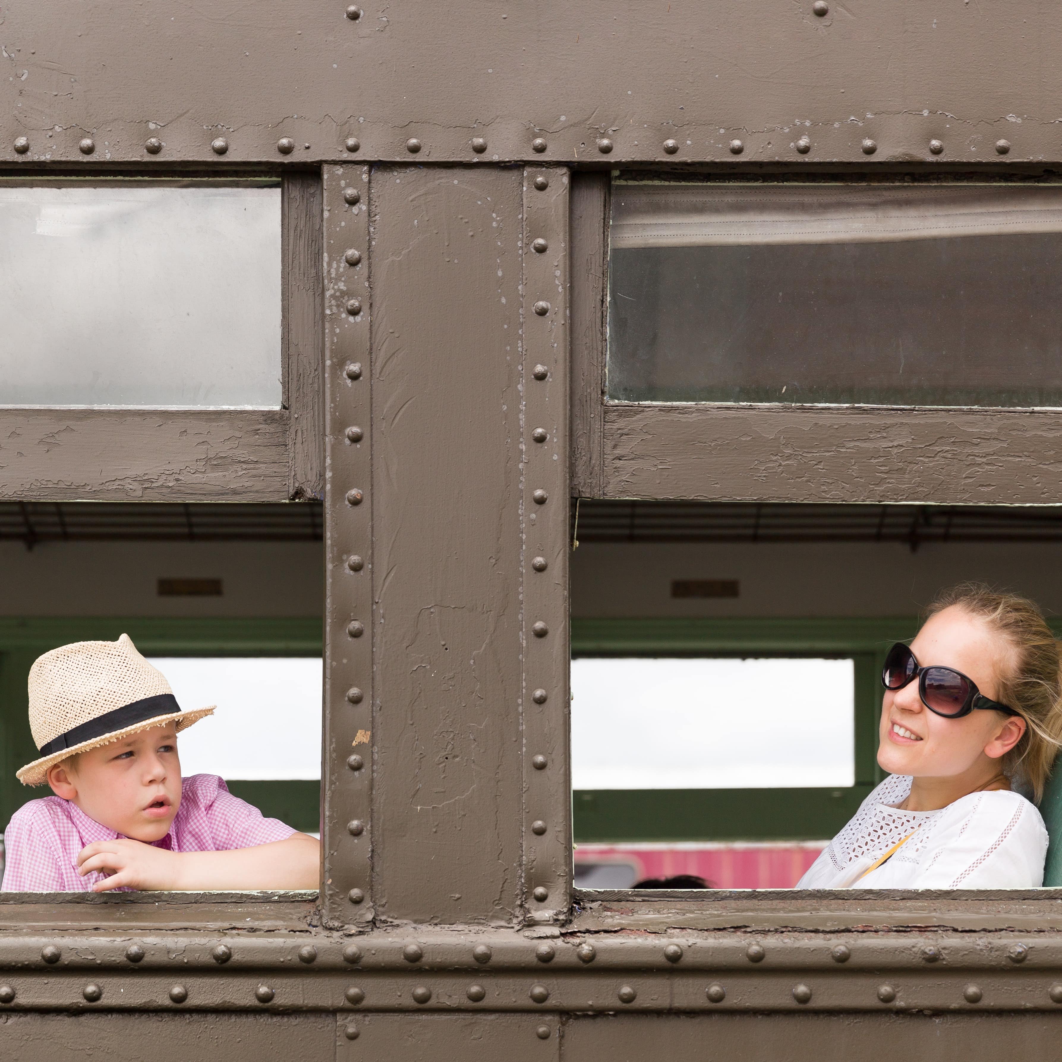 Happy mother and son sitting in the old train and looking out the window