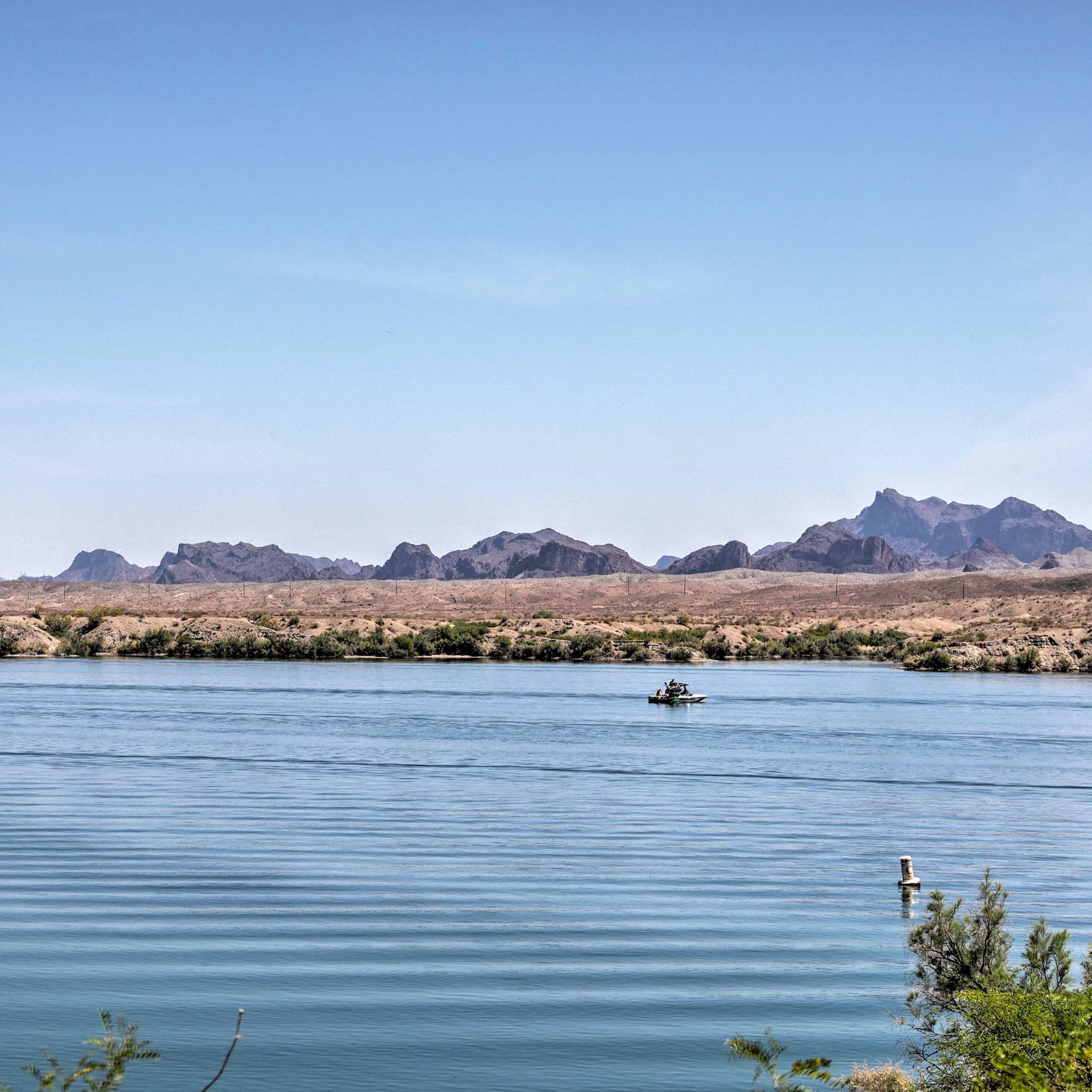 A boat sails on Lake Havasu with mountains in the distance