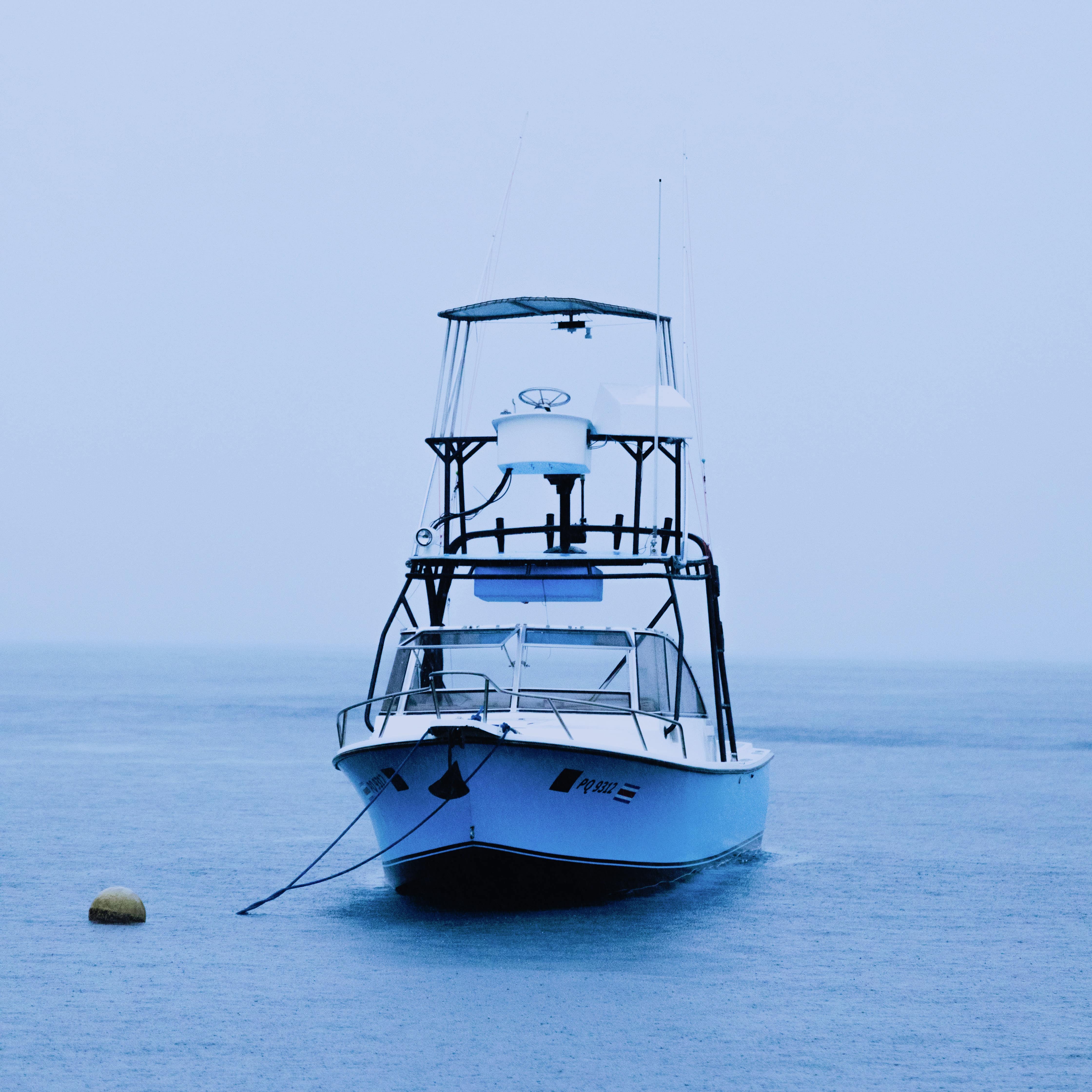 Small blue fishing boat moored on a buoy