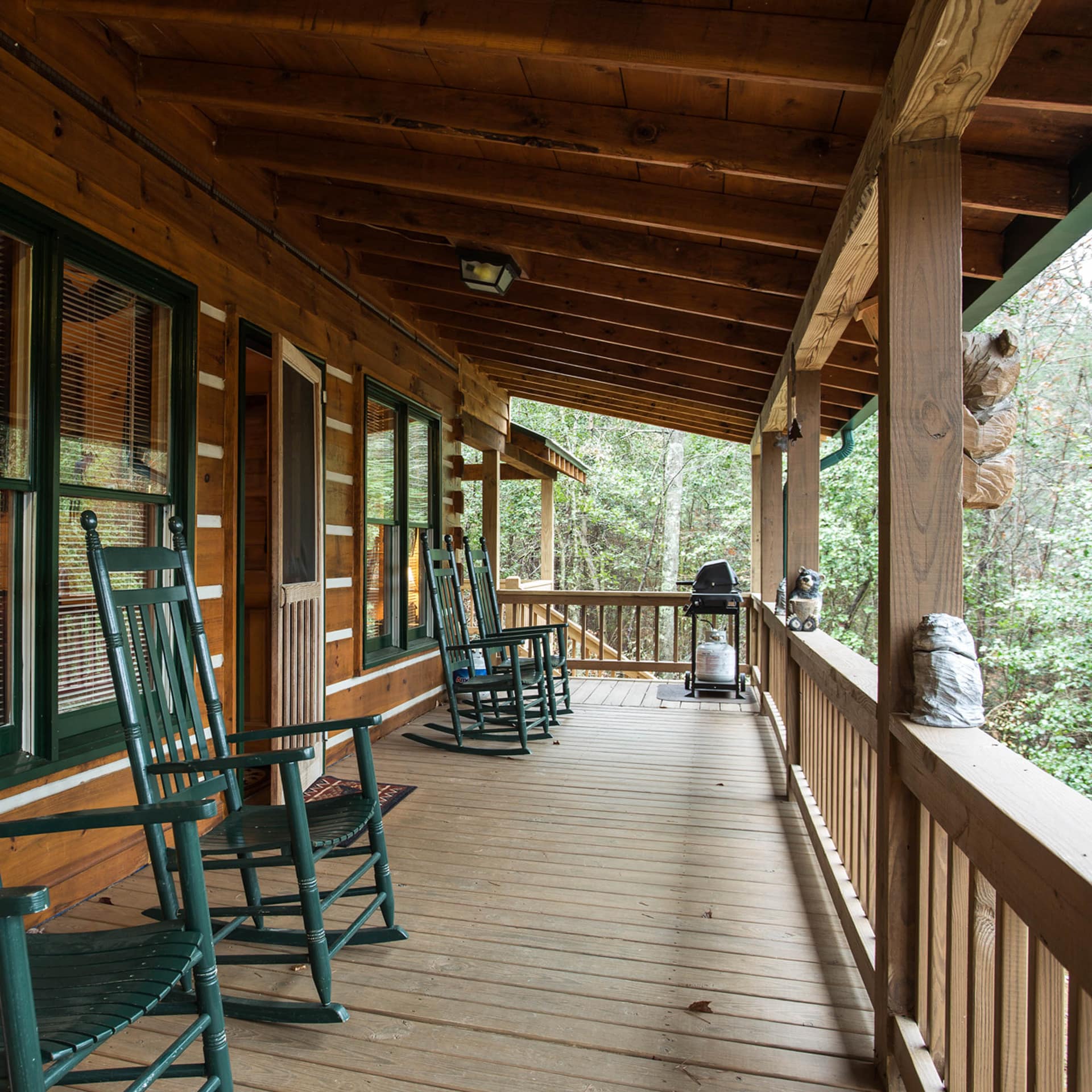 Green rocking chairs and a BBQ grill look out from the porch of a mountain getaway in Georgia