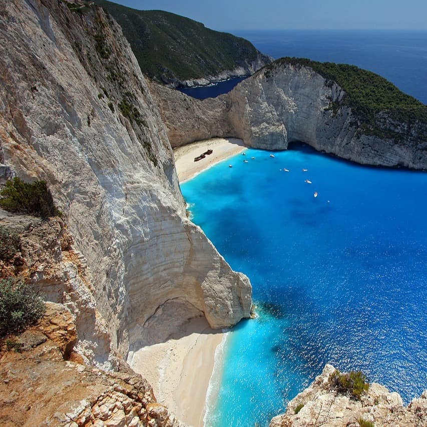 Yachts cluster beneath the white cliffs of iconic Shipwreck Beach in Zakynthos