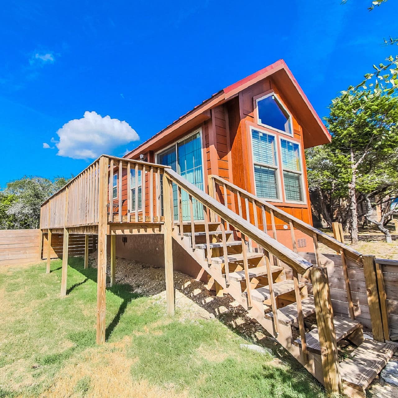 The sun drenches a wood-built cabin with a deck in the Texan Hill Country 