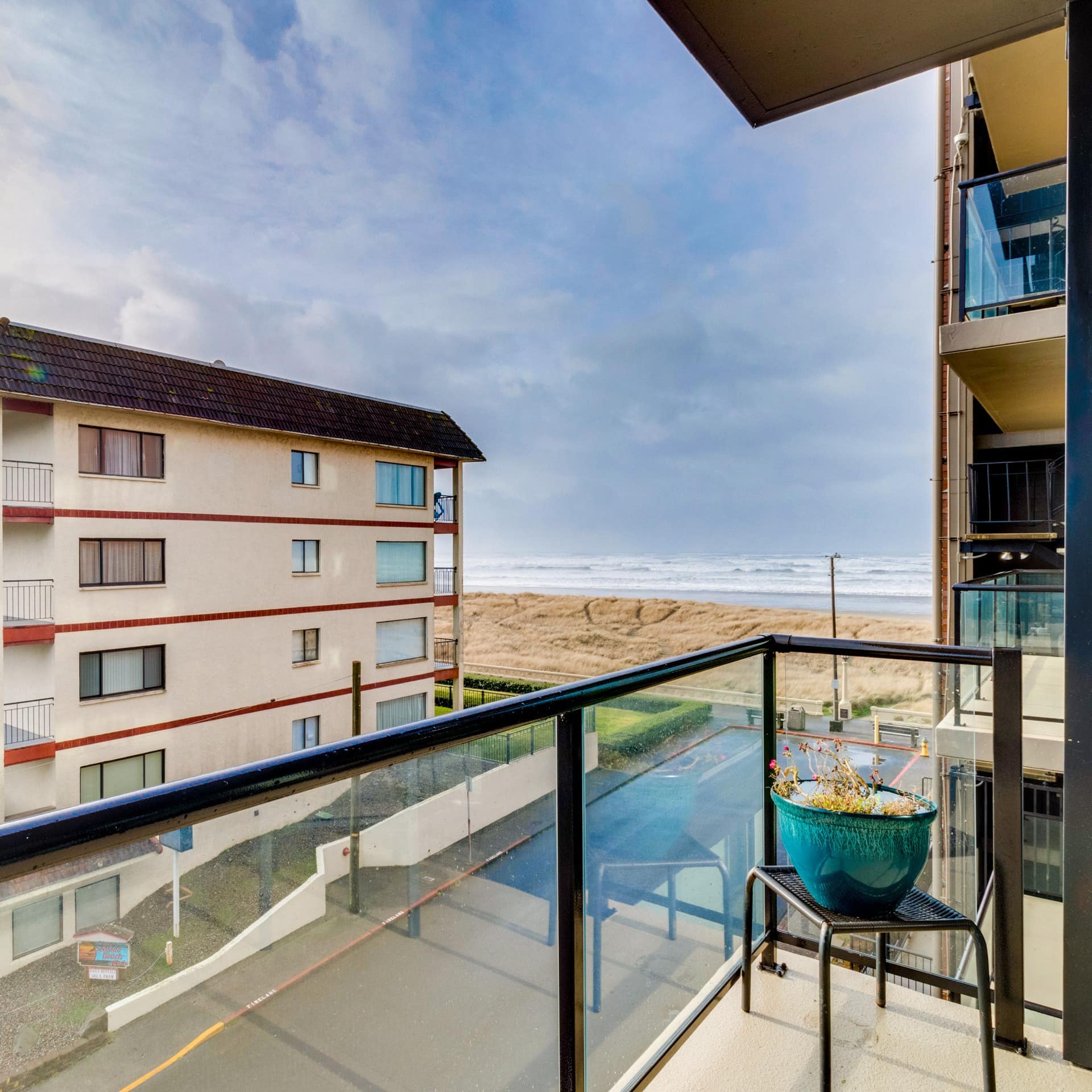 A condo block rises just behind the dunes of Seaside with a balcony view of the ocean