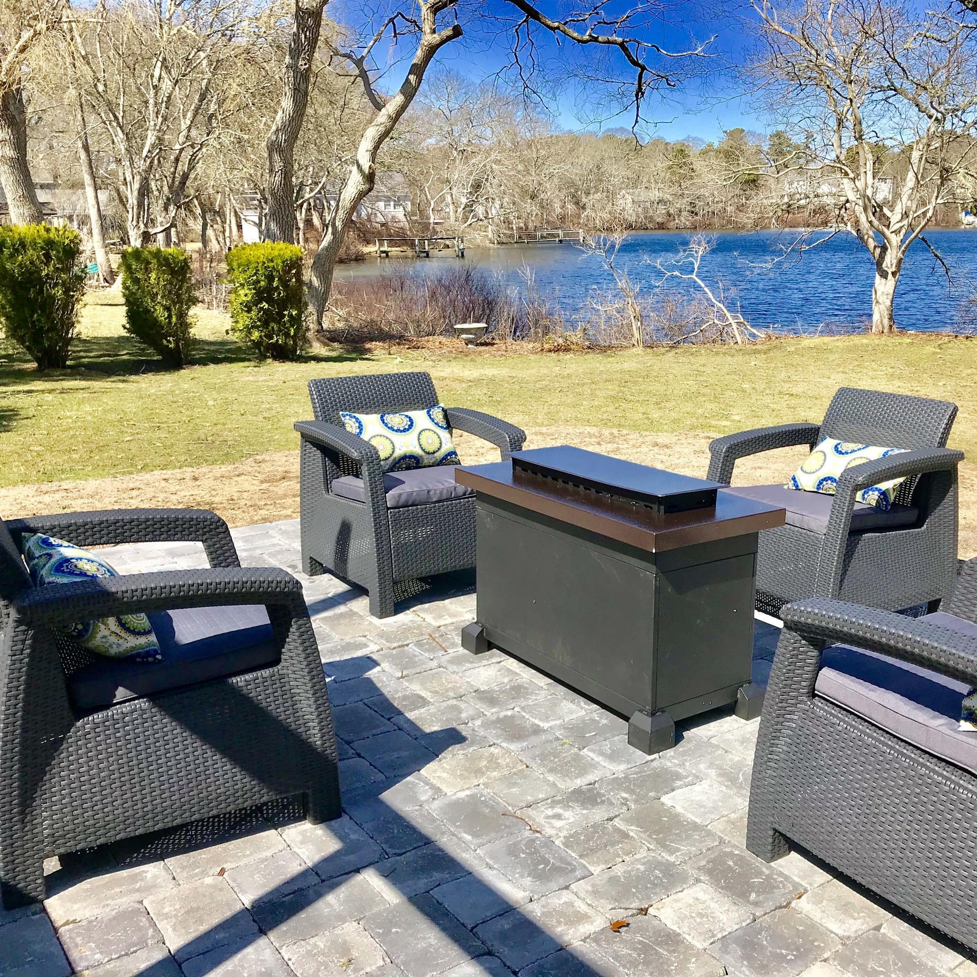 Wicker furniture on the stone-flagged patio of a pet-friendly vacation home by the water in Cape Cod