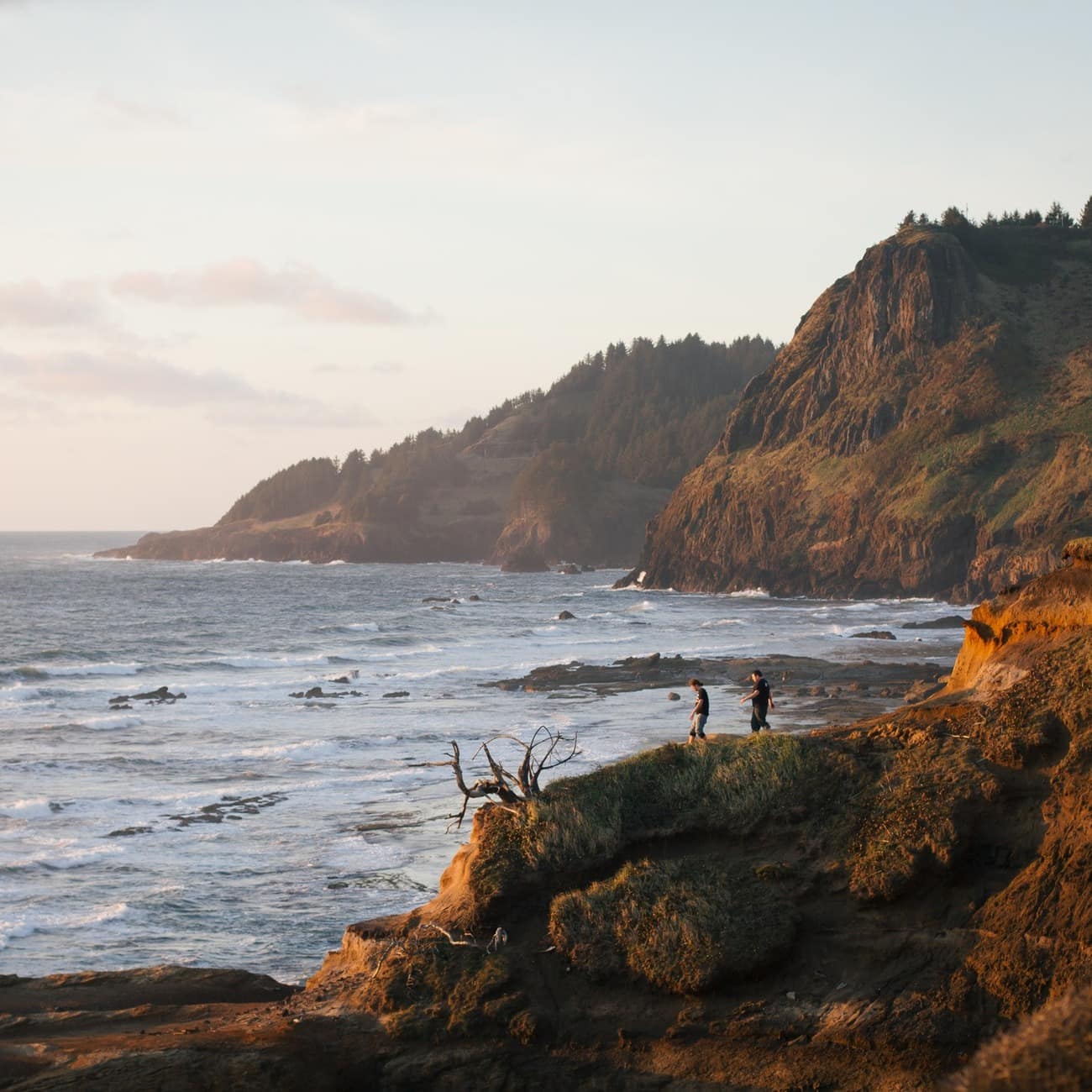 Two people stroll along the rugged cliffs and rocks of the Oregon coast in California