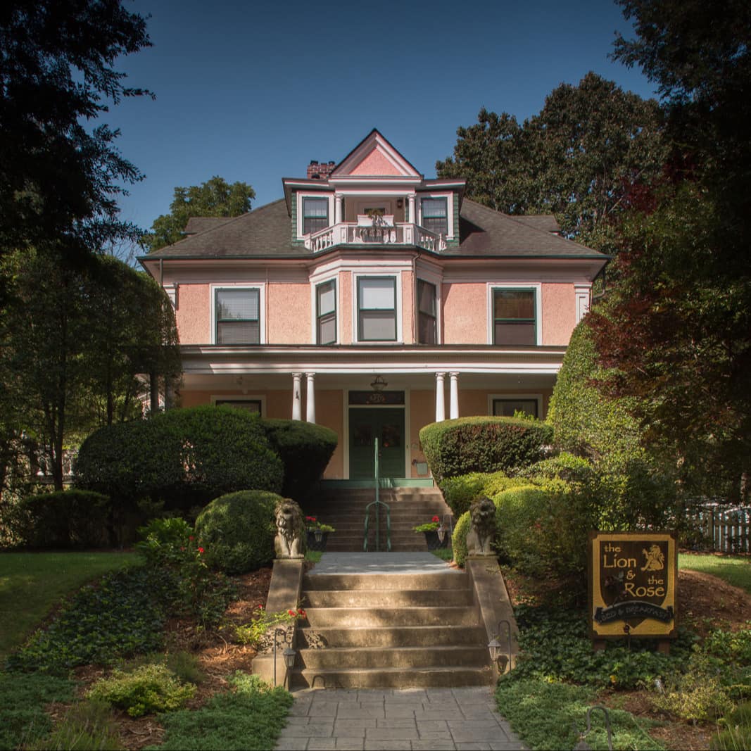 A pink-painted B&B in Asheville with a manicured yard and steps leading to its front door