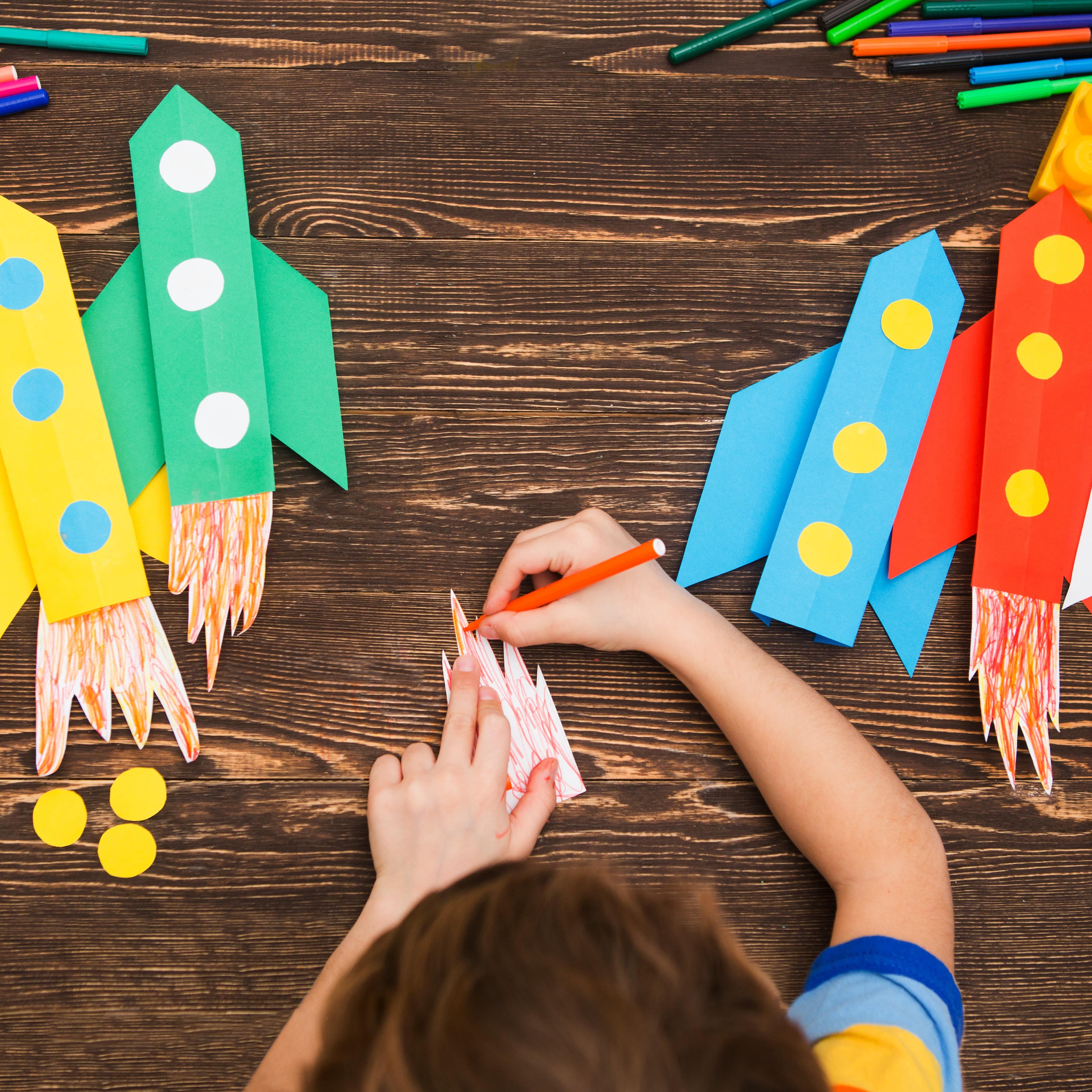 Child making colorful rockets from paper