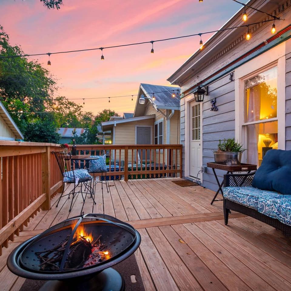 A fire pit flickers on the deck of a cozy cottage in San Antonio, Texas