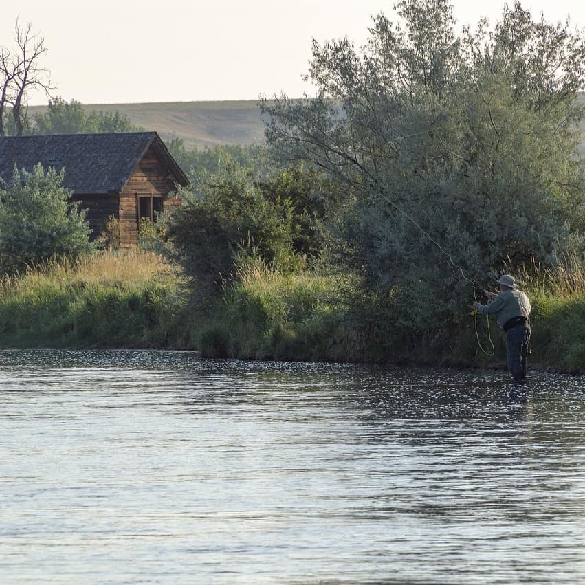 Cabin on a river with an angler fishing in the foreground