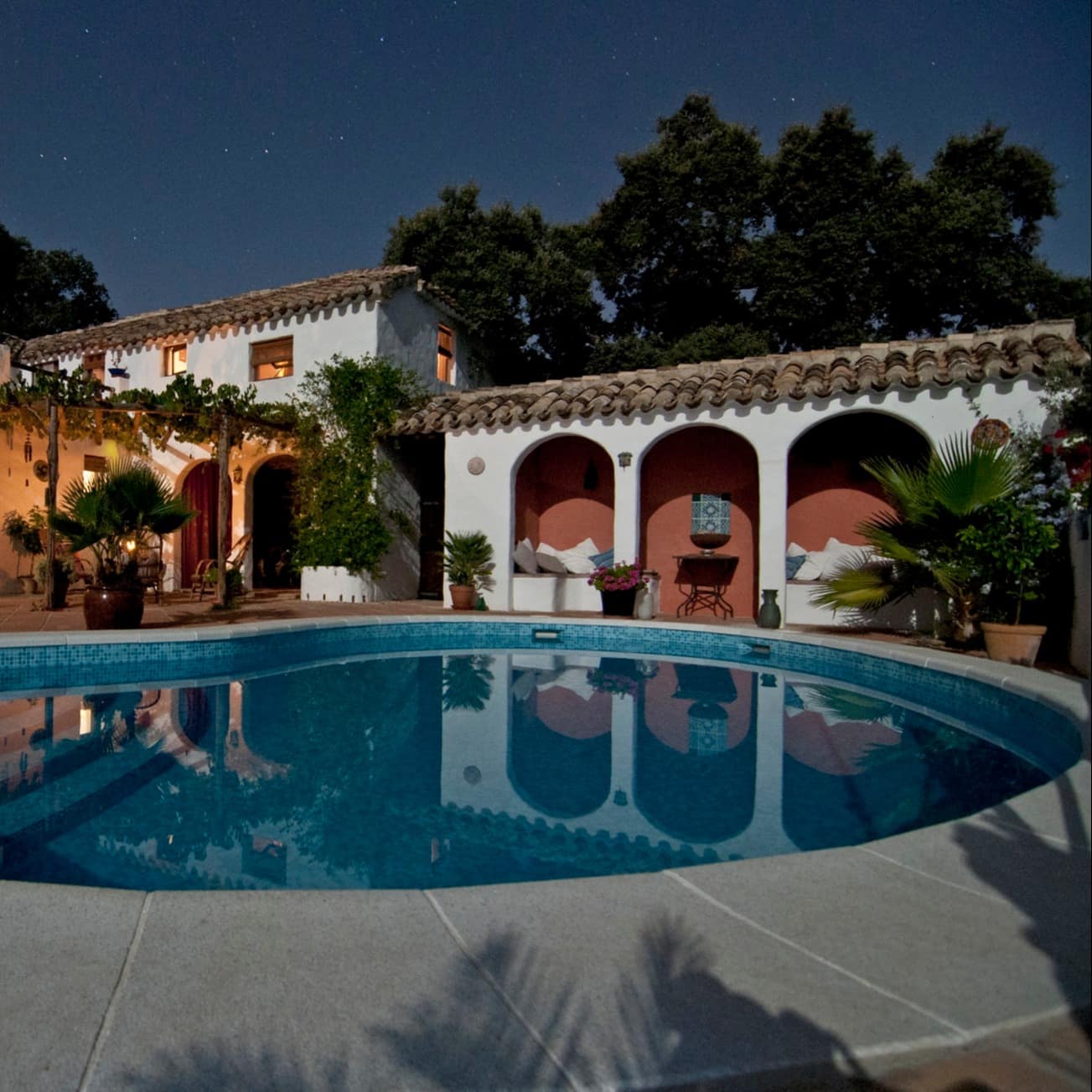 A traditional Spanish mansion at night with a pool out front