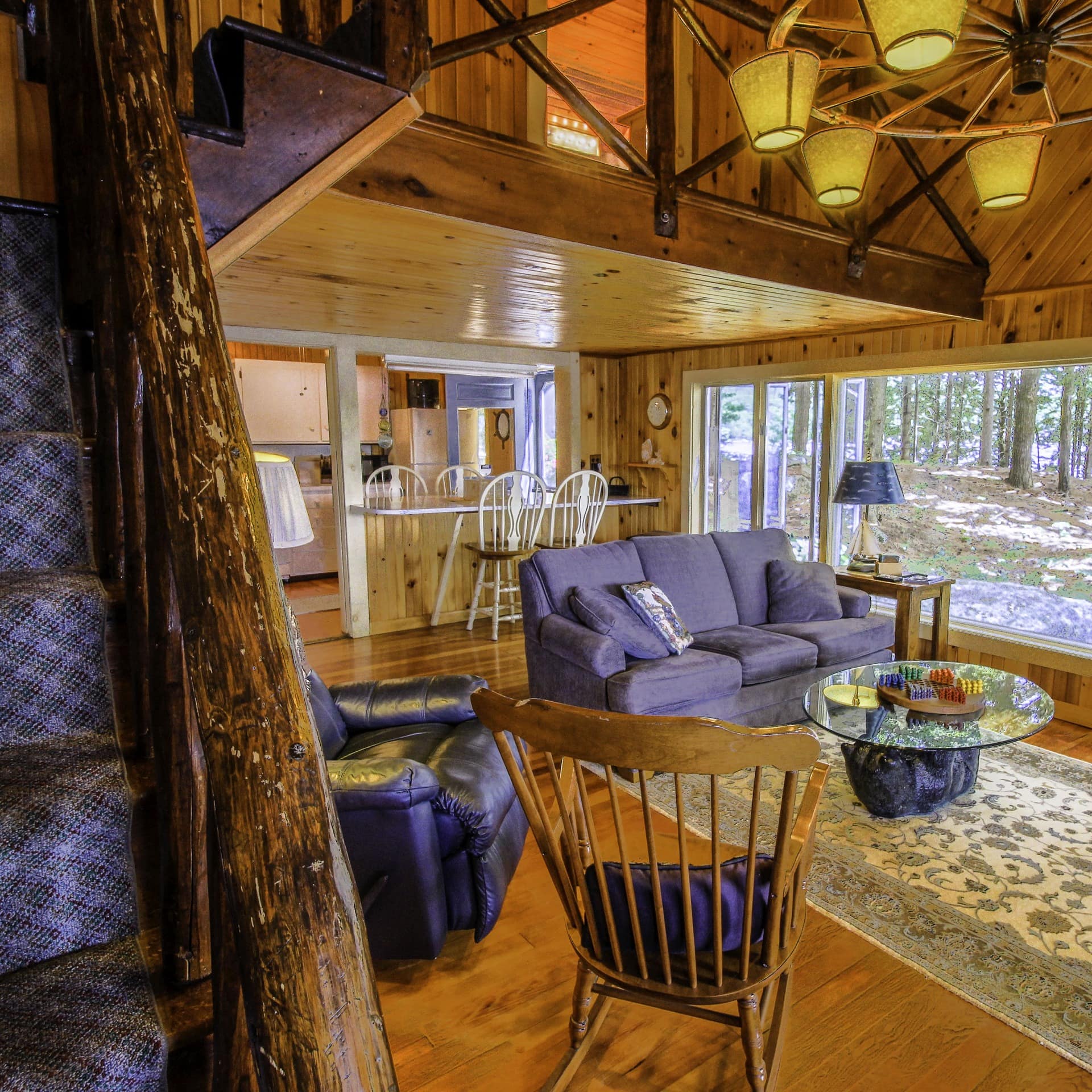 This cabin rental near Acadia National Park features hardwood interiors, colorful furnishings, and large windows offering views of the surrounding woods