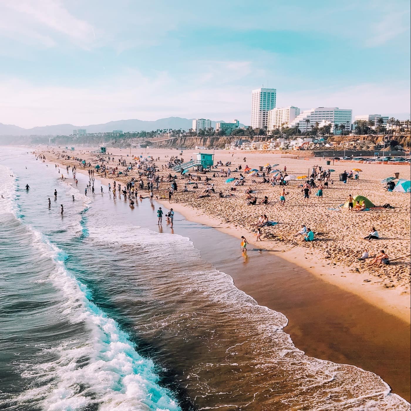 A beach lined with condos and high-rises is filled with families and swimmers