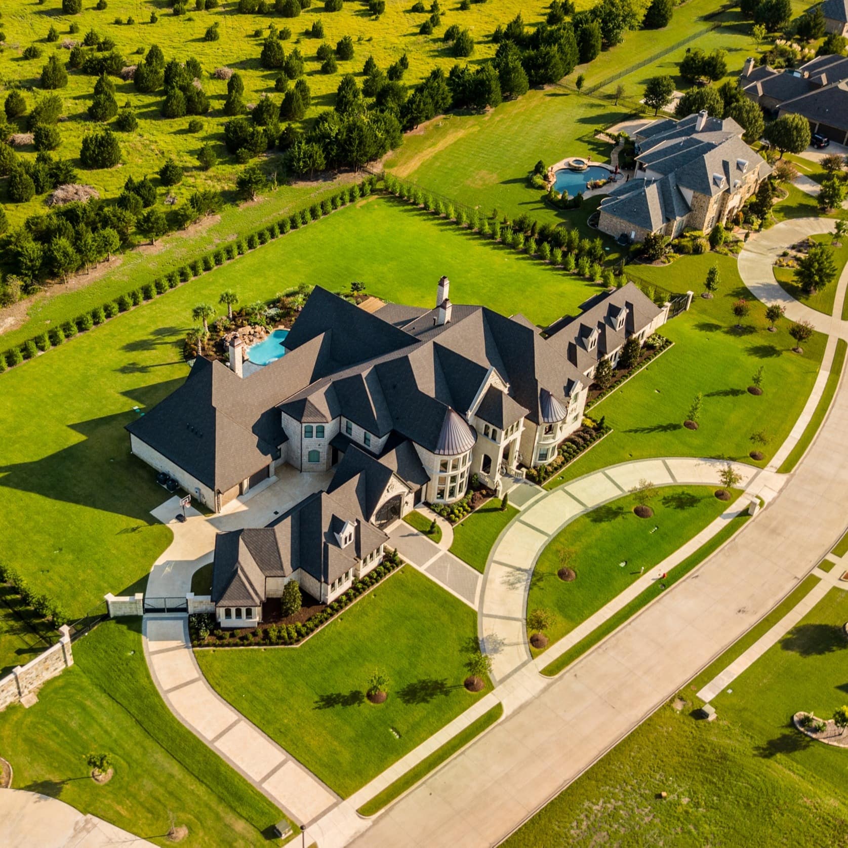 A huge mansion with a swimming pool and big green lawns