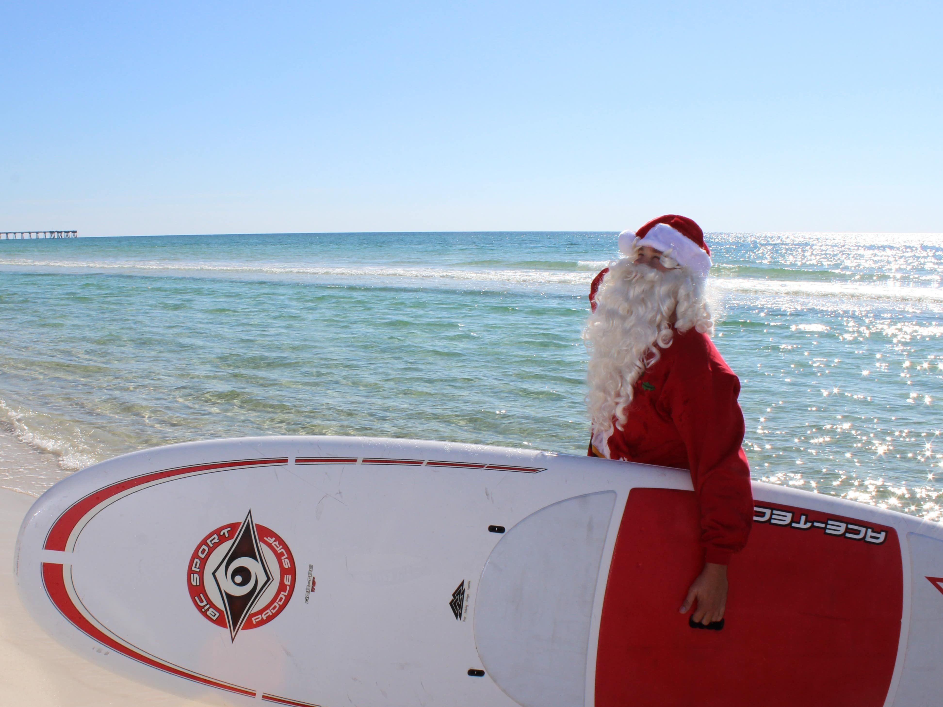santa on the beach with a red and white paddleboard