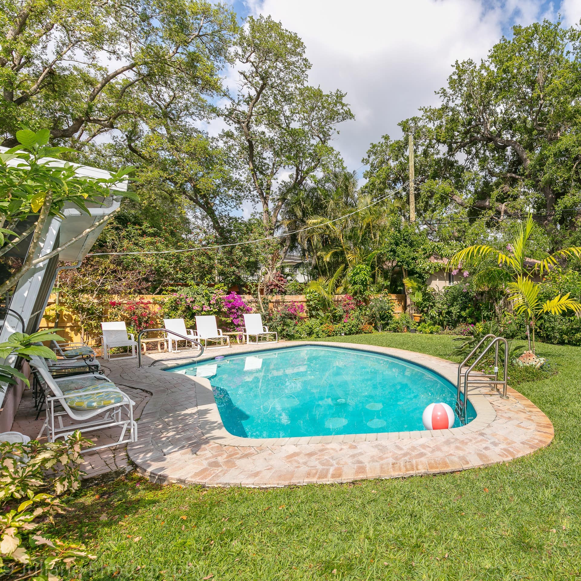 A family villa in Fort Lauderdale with a pool and deckchairs in a grassy garden