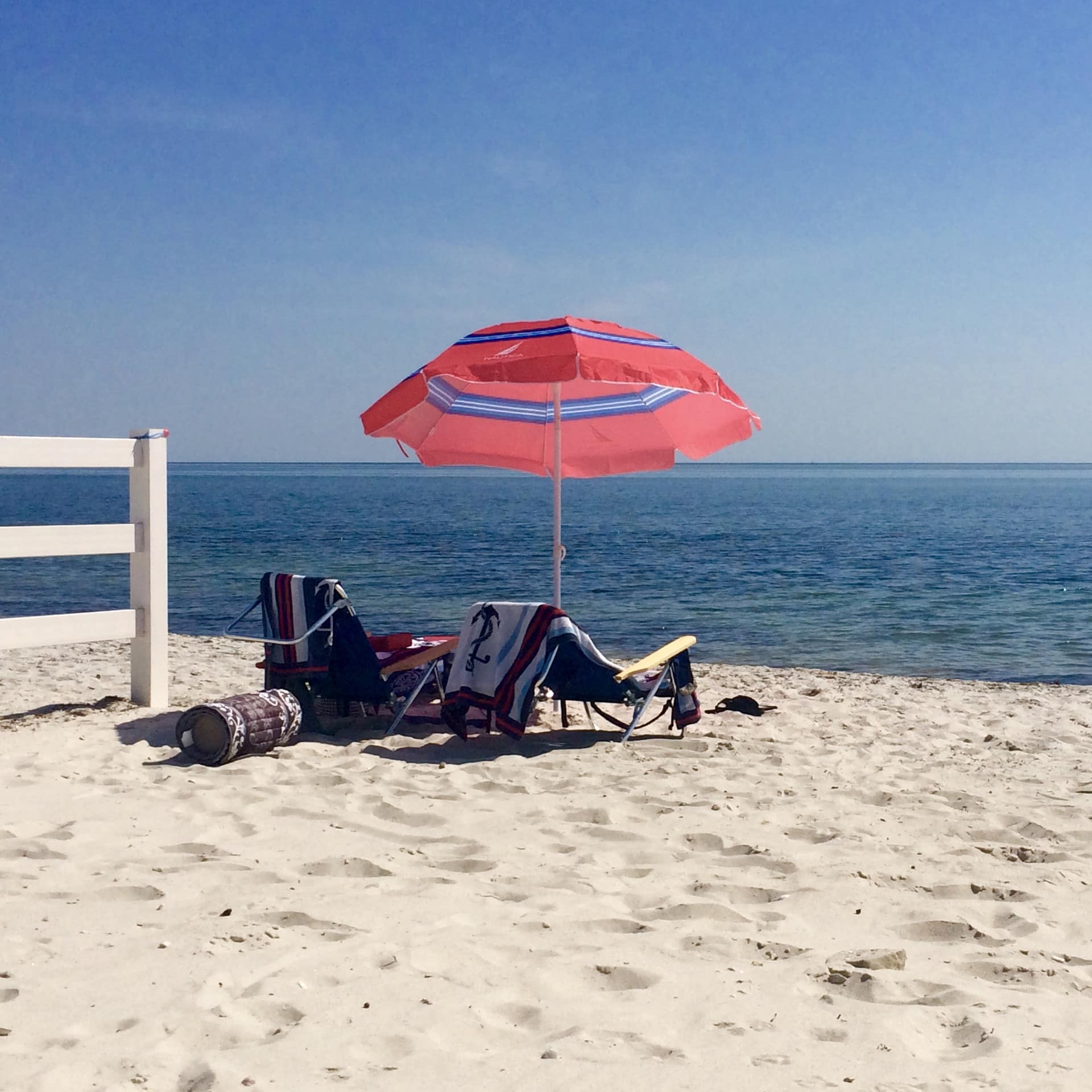 Umbrella-shaded beach chairs on white sand, facing the ocean