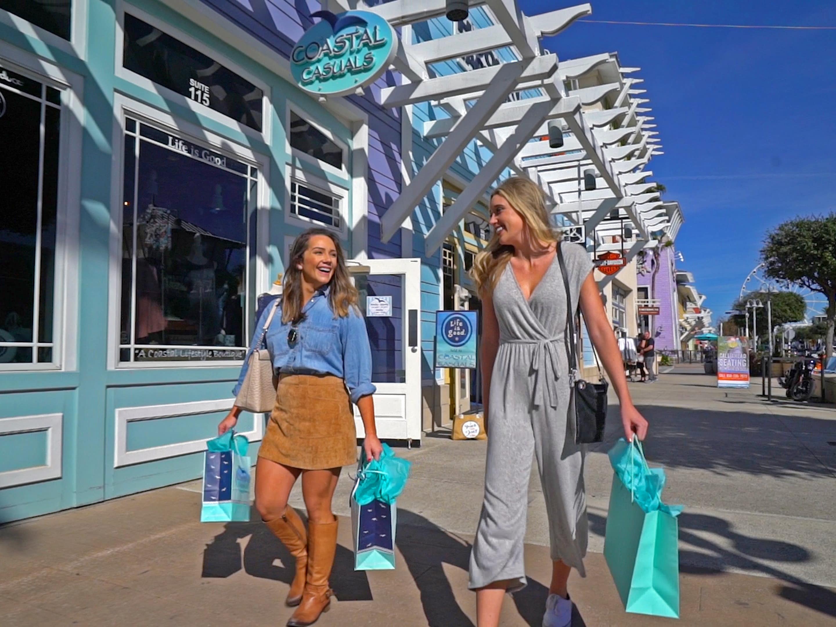 two women shopping at pier park with teal shopping bags