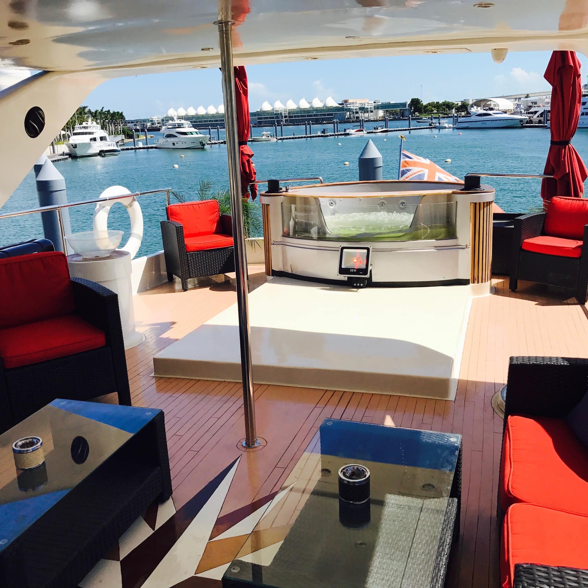 A hot tub, tables, and chairs on the deck of a luxury yacht