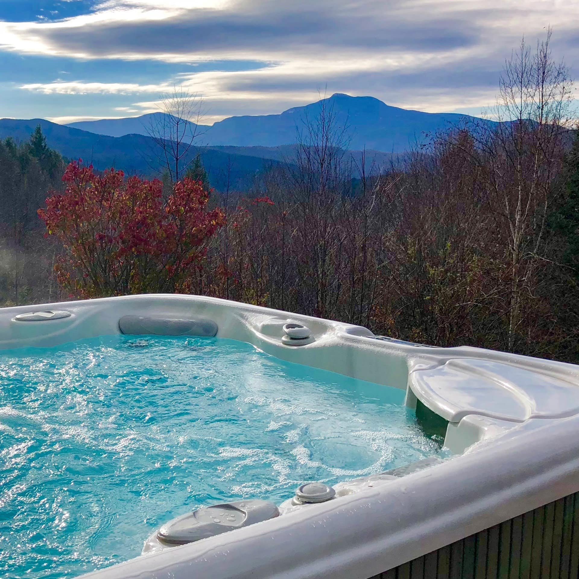 A cabin rental's outdoor hot tub looking out onto mountains in the distance