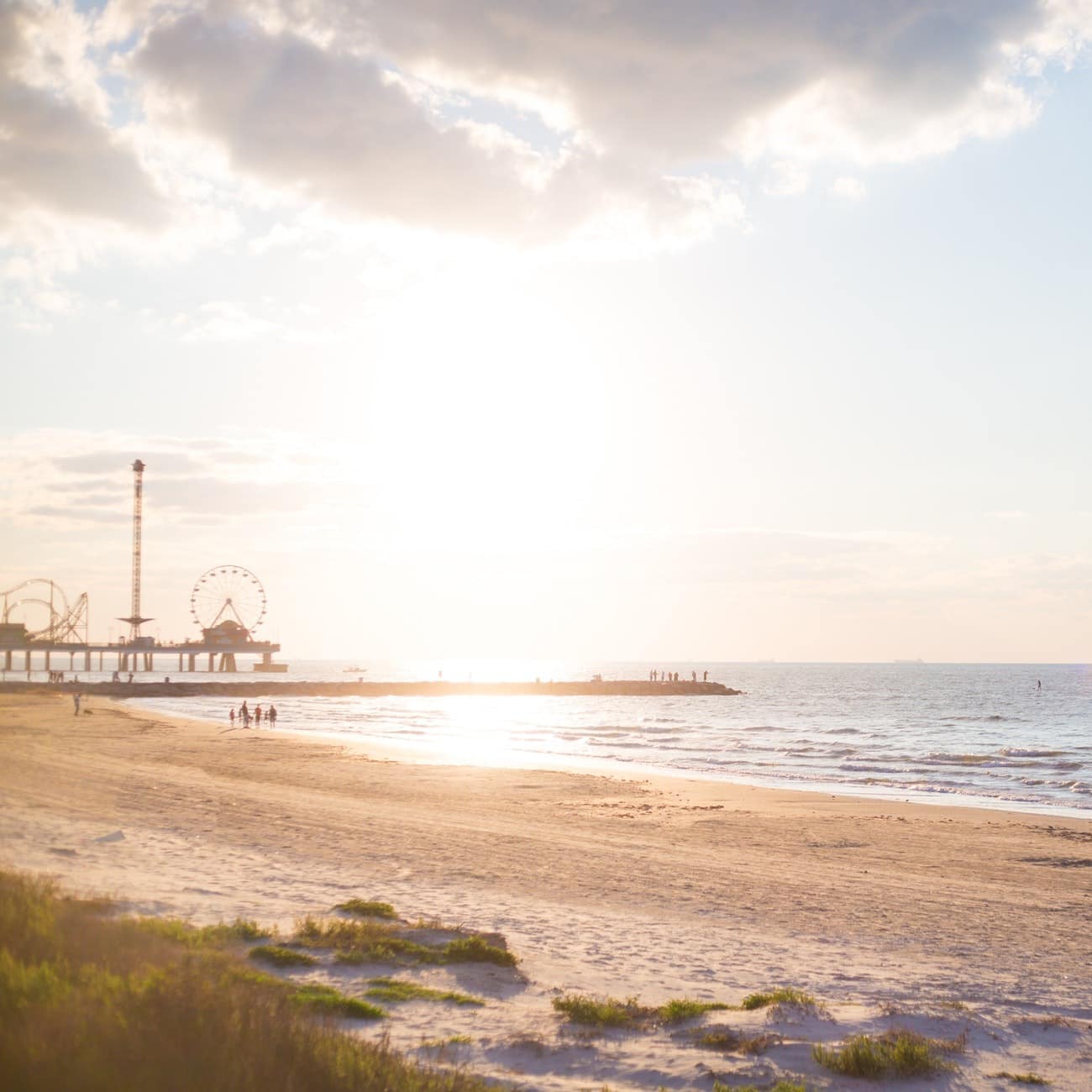 Galveston beach at sunrise with the Pleasure Pier silhouetted by some dunes