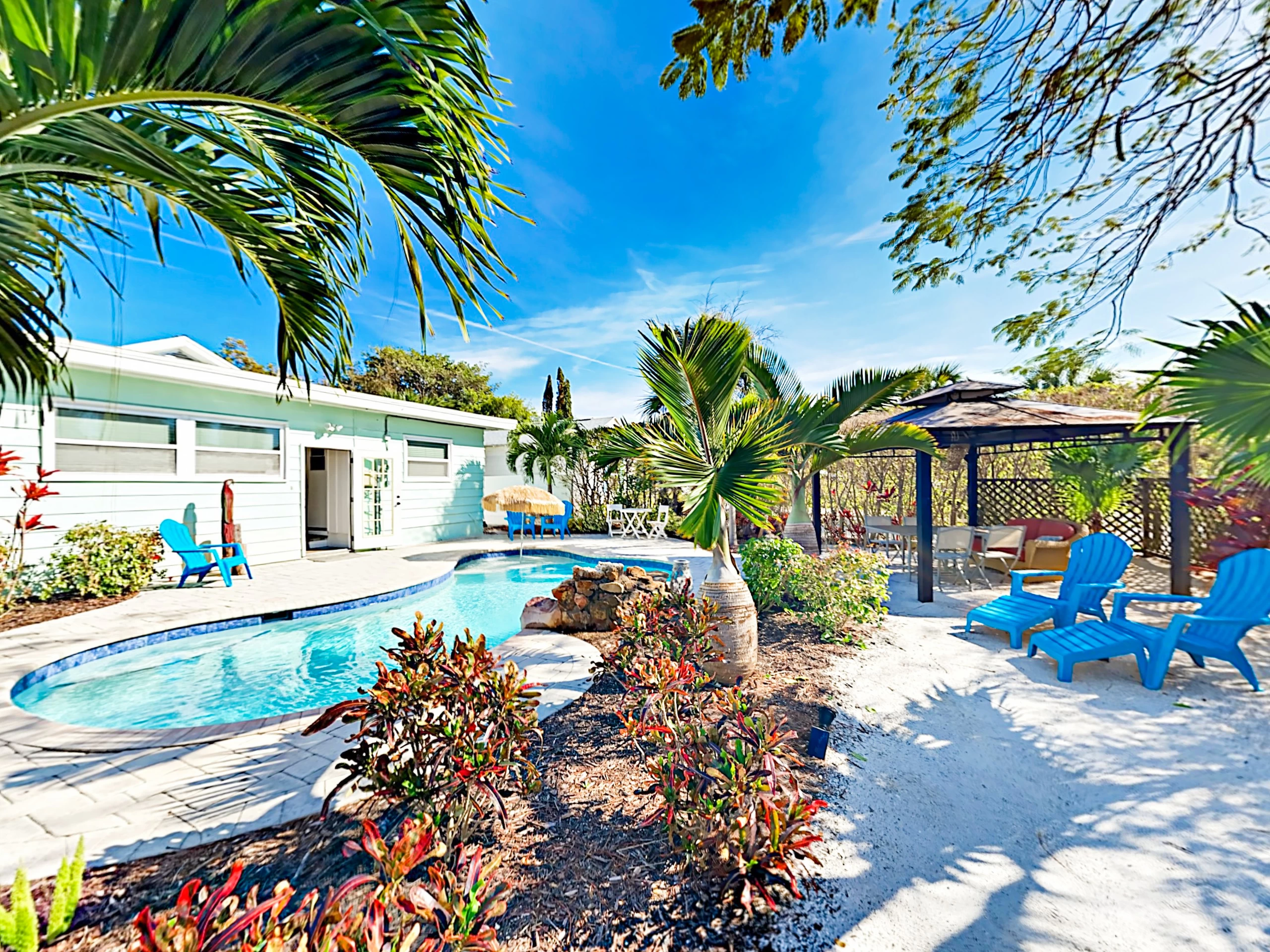 This home has a private pool and cabana surrounded by sand and palm trees.