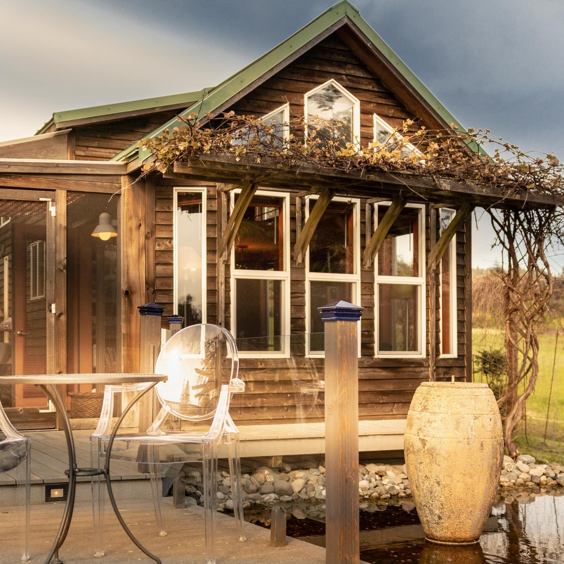 Wooden cabin with a pond outside and chairs on the deck