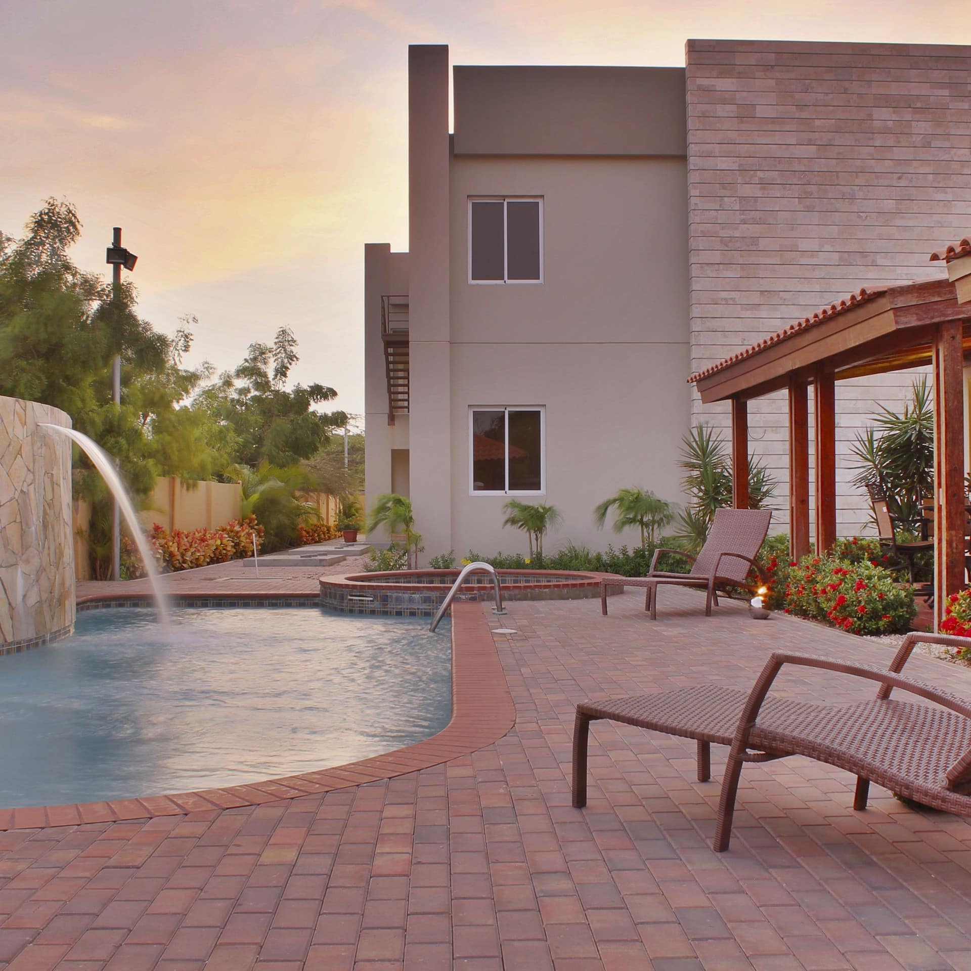 A stunning luxury villa in Aruba at sunset, with deck chairs and a swimming pool in its grounds