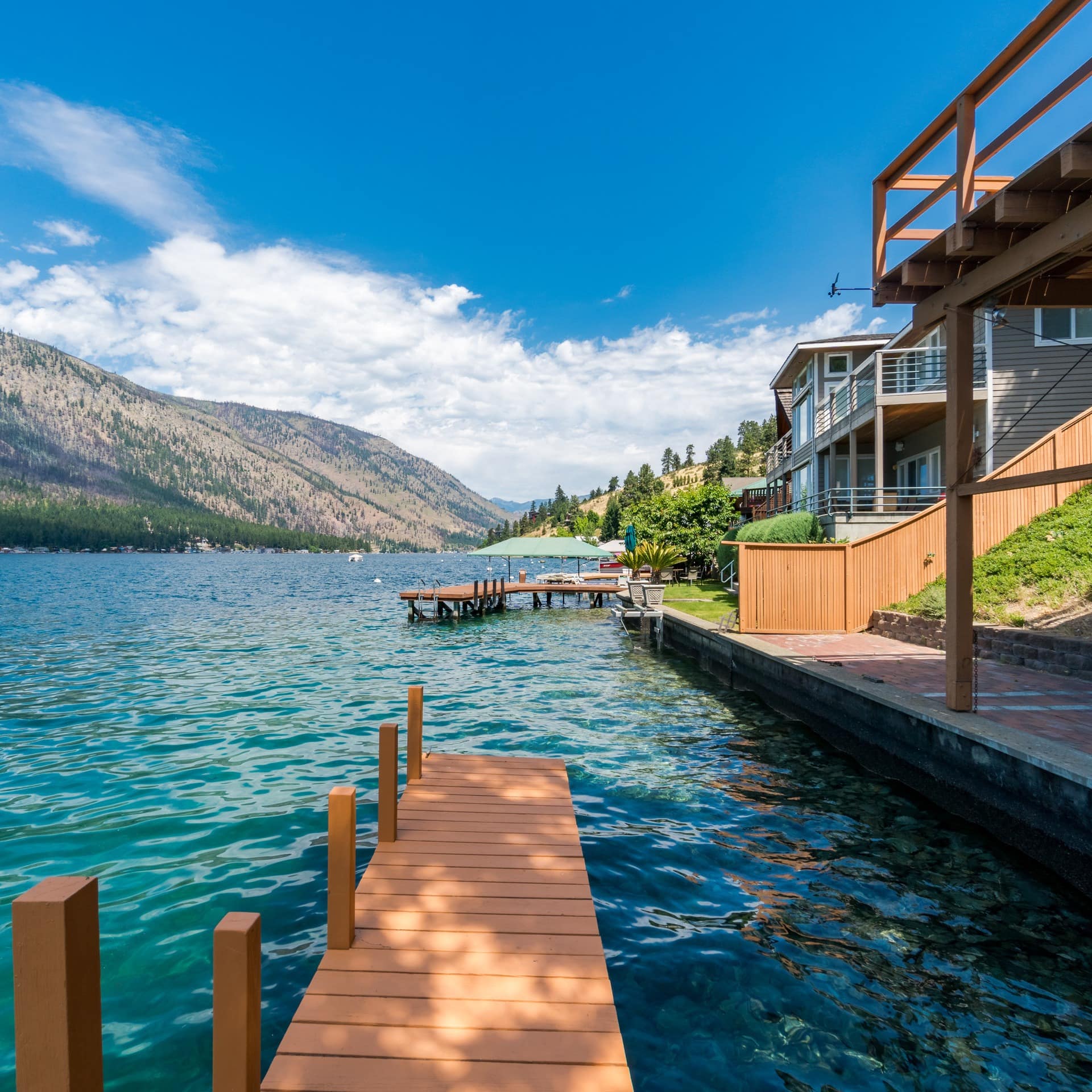A dock overlooking a blue lake with mountains and houses on either side