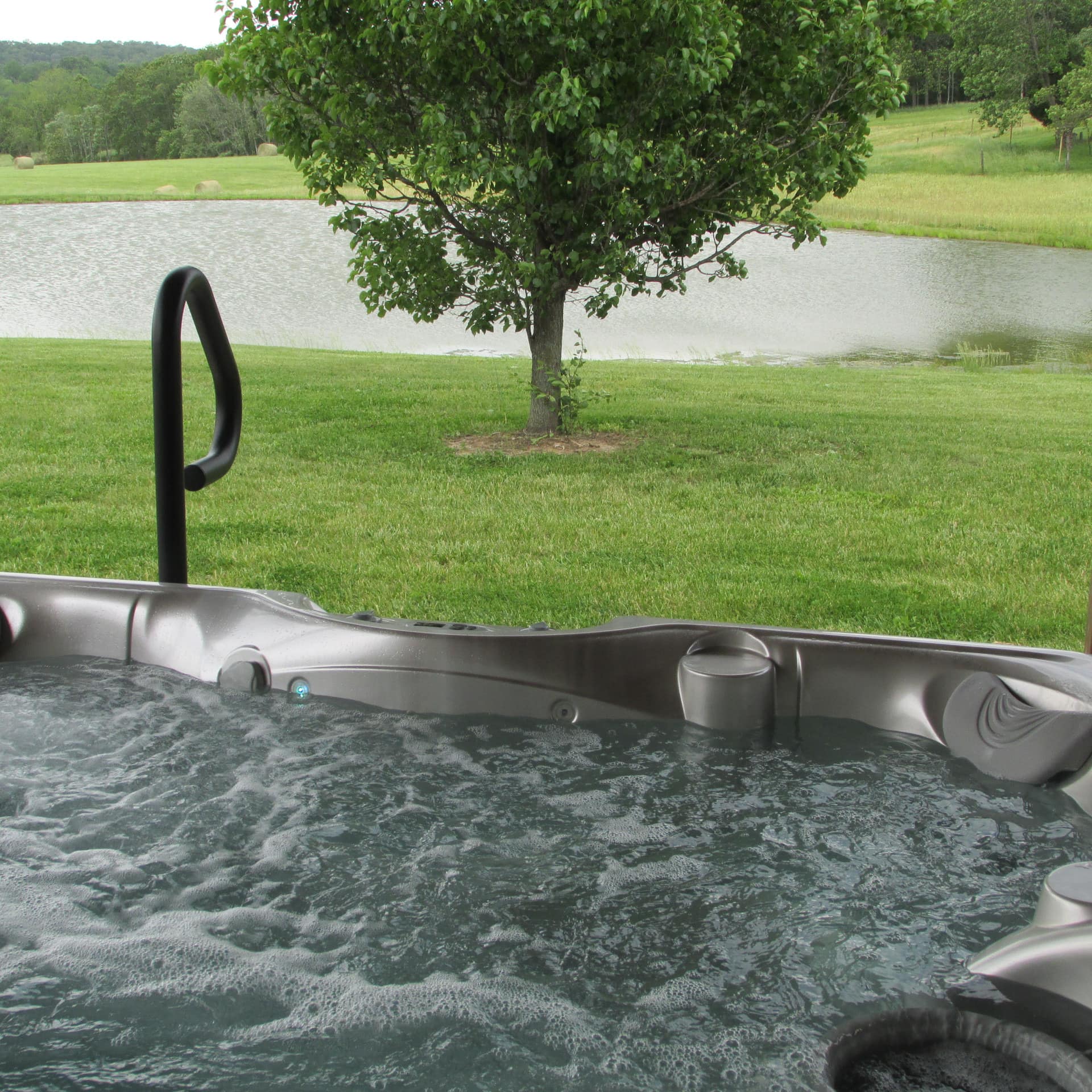 Hot tub overlooking lawns, trees, and a pond