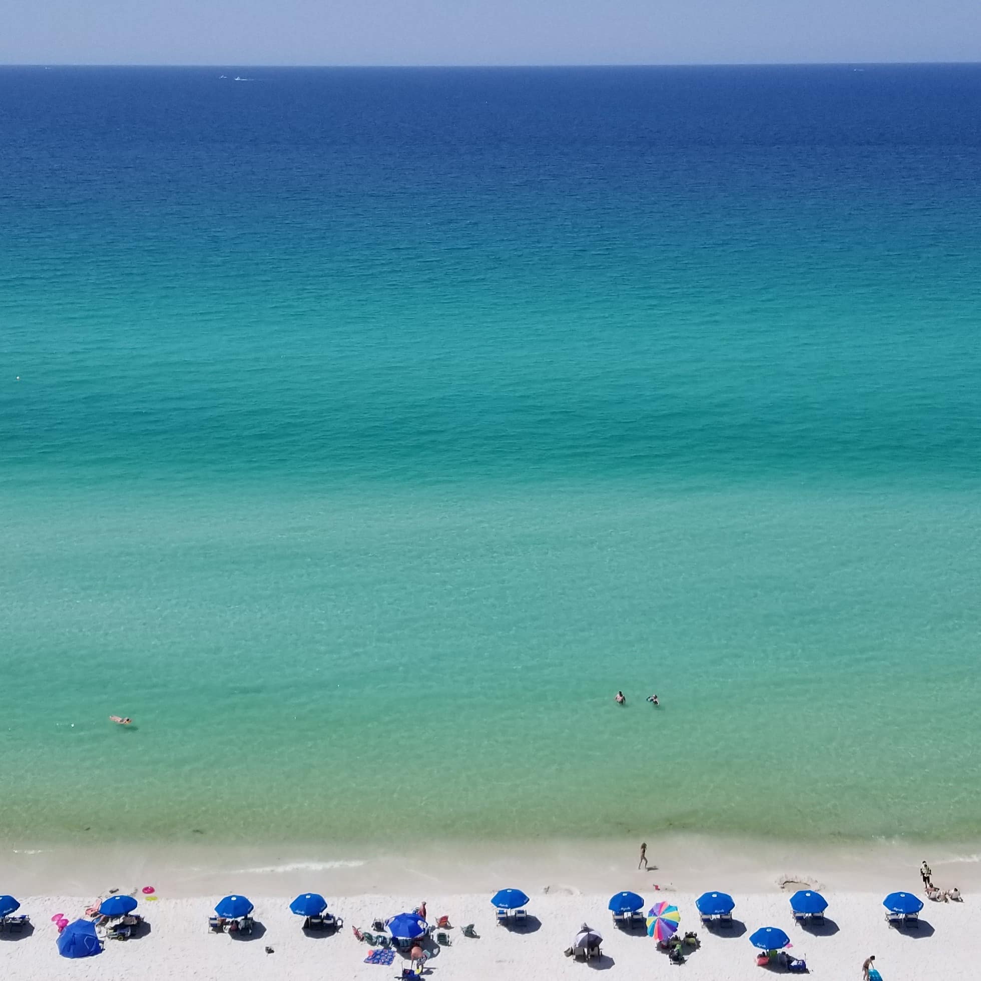 Beach umbrellas on white sand facing the crystalline blue waters at Panama City Beach