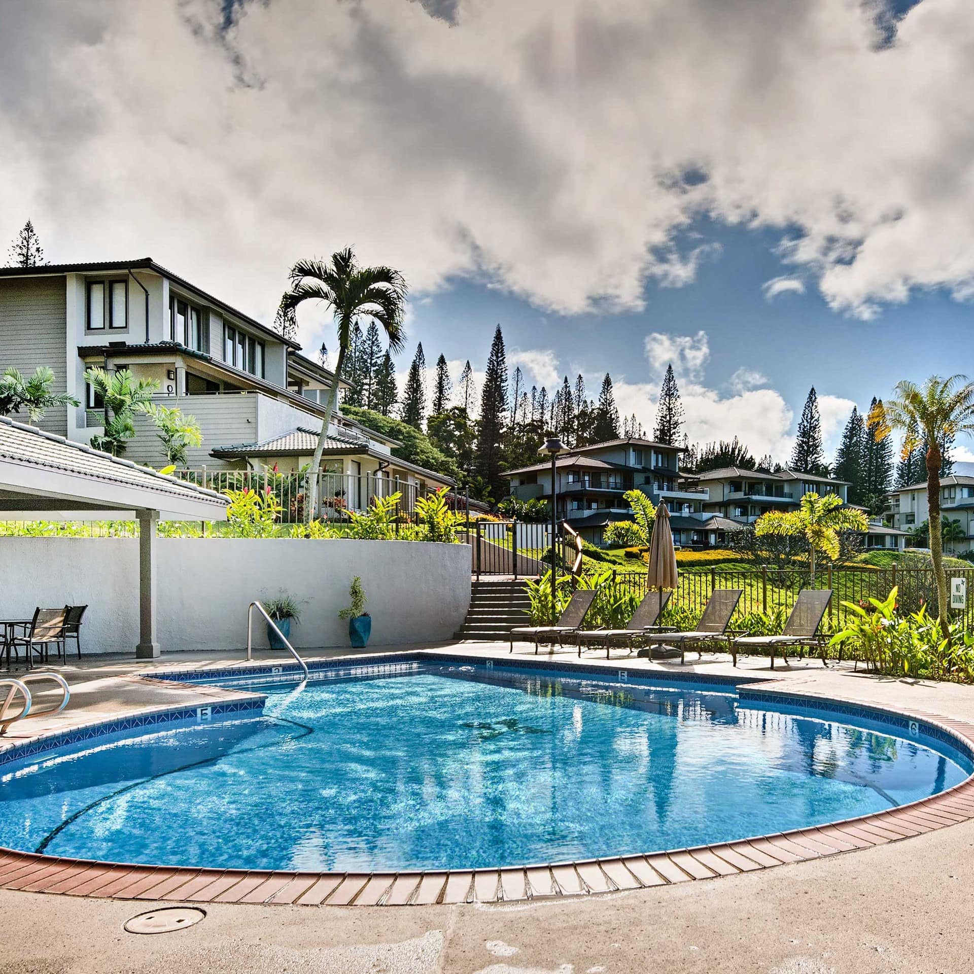 A villa in Kapalua with a shared pool area and vistas of palm-speckled hills out front