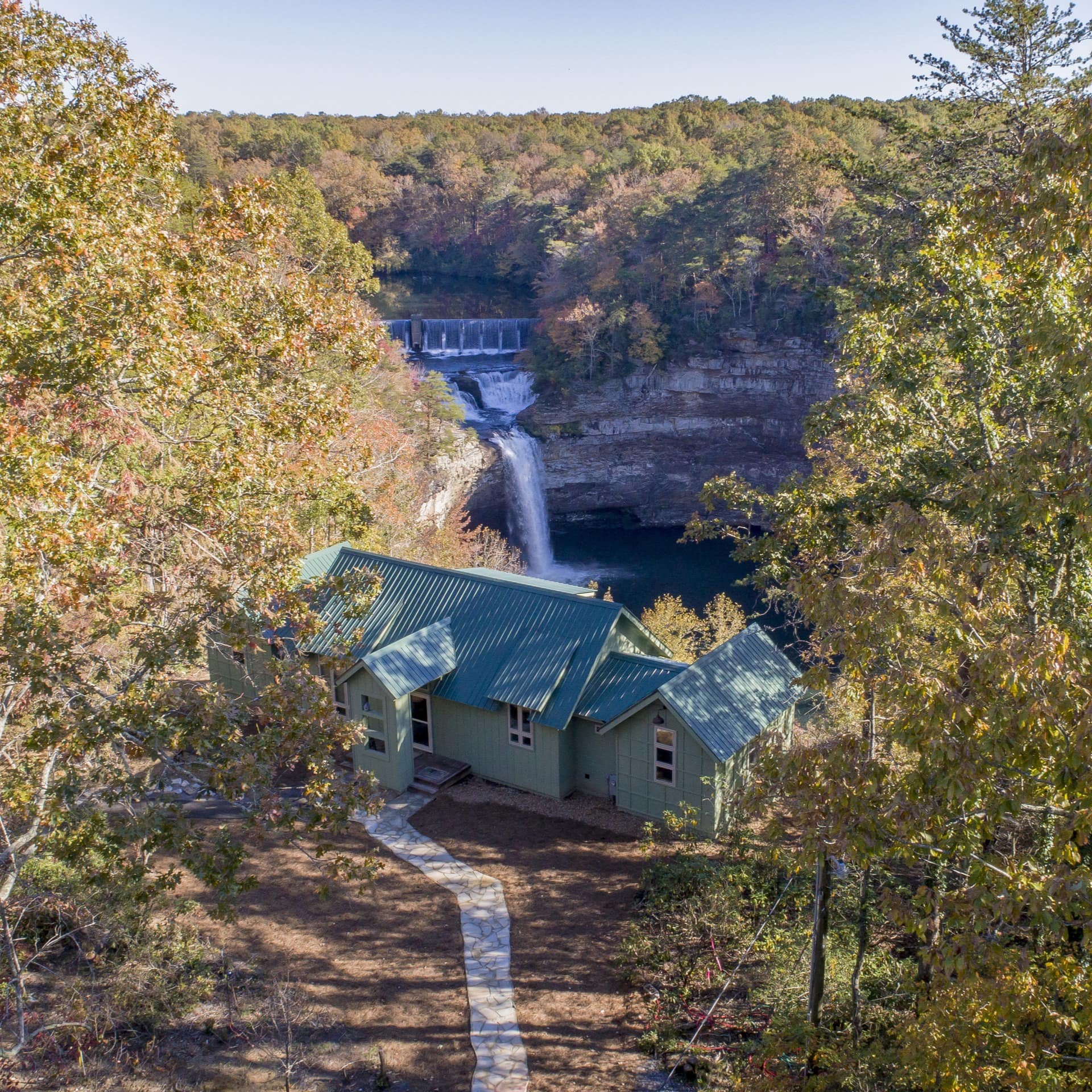 Green forest cabin overlooking a waterfall and lake Image