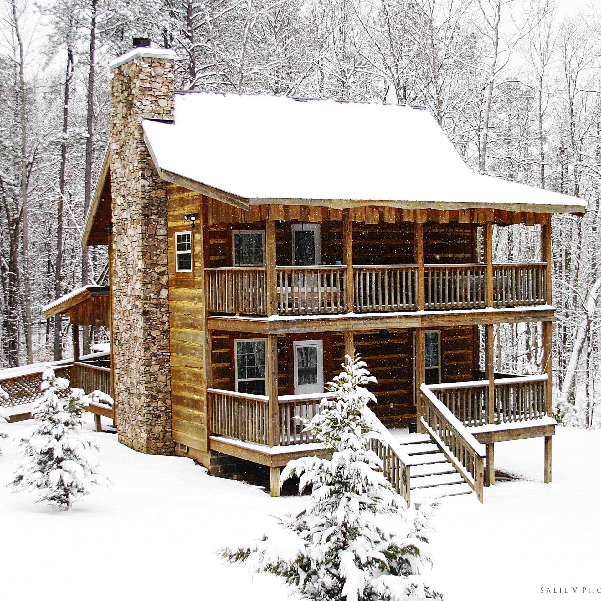 Large log cabin in the woods, covered in snow