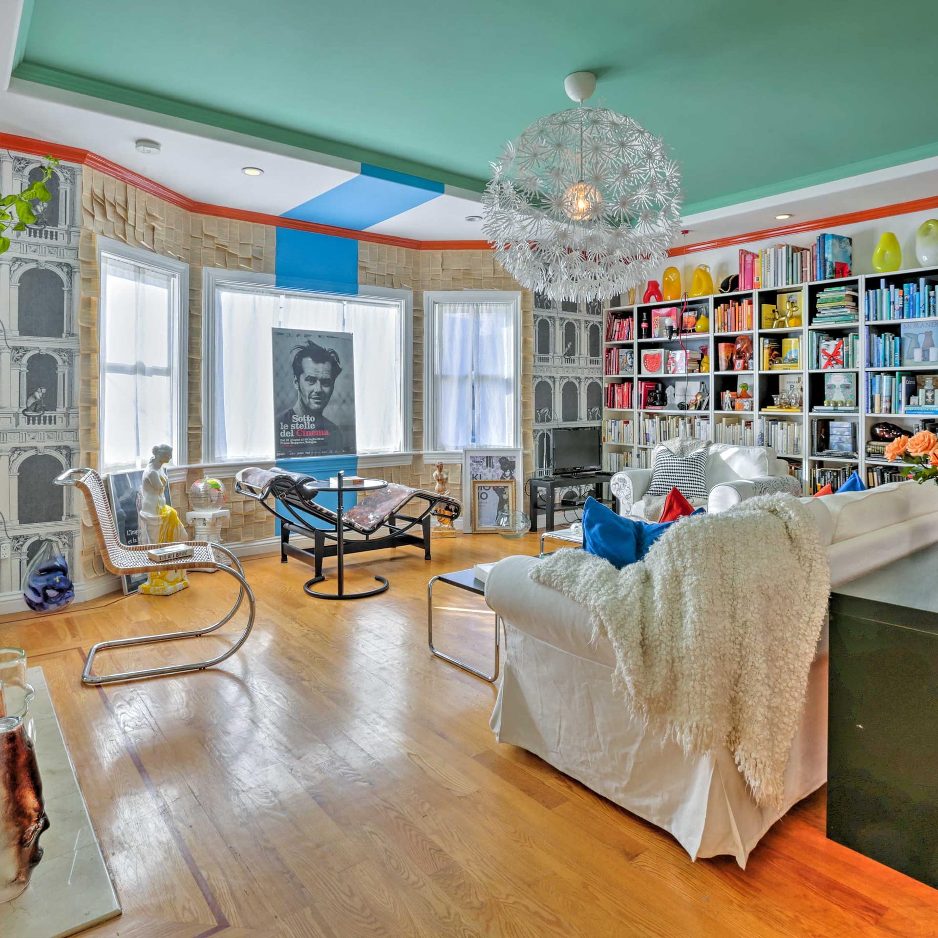 A stylish living room with a colorful library and vibrant contemporary artwork
