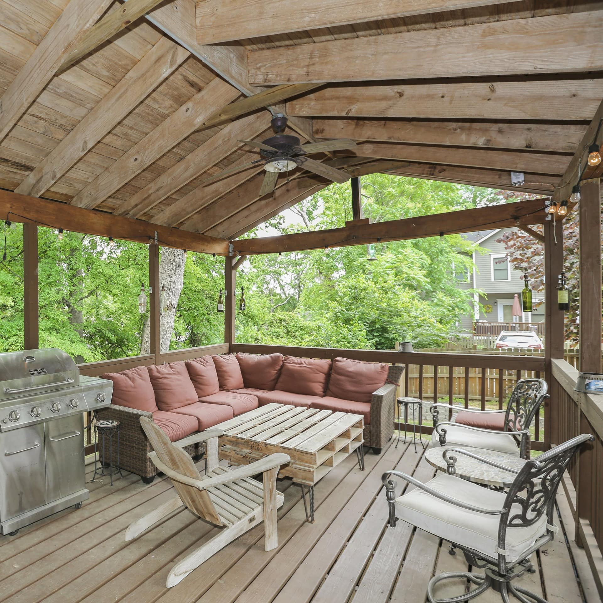 Barbecue grills, chairs, and a table on the covered deck of a vacation home rental