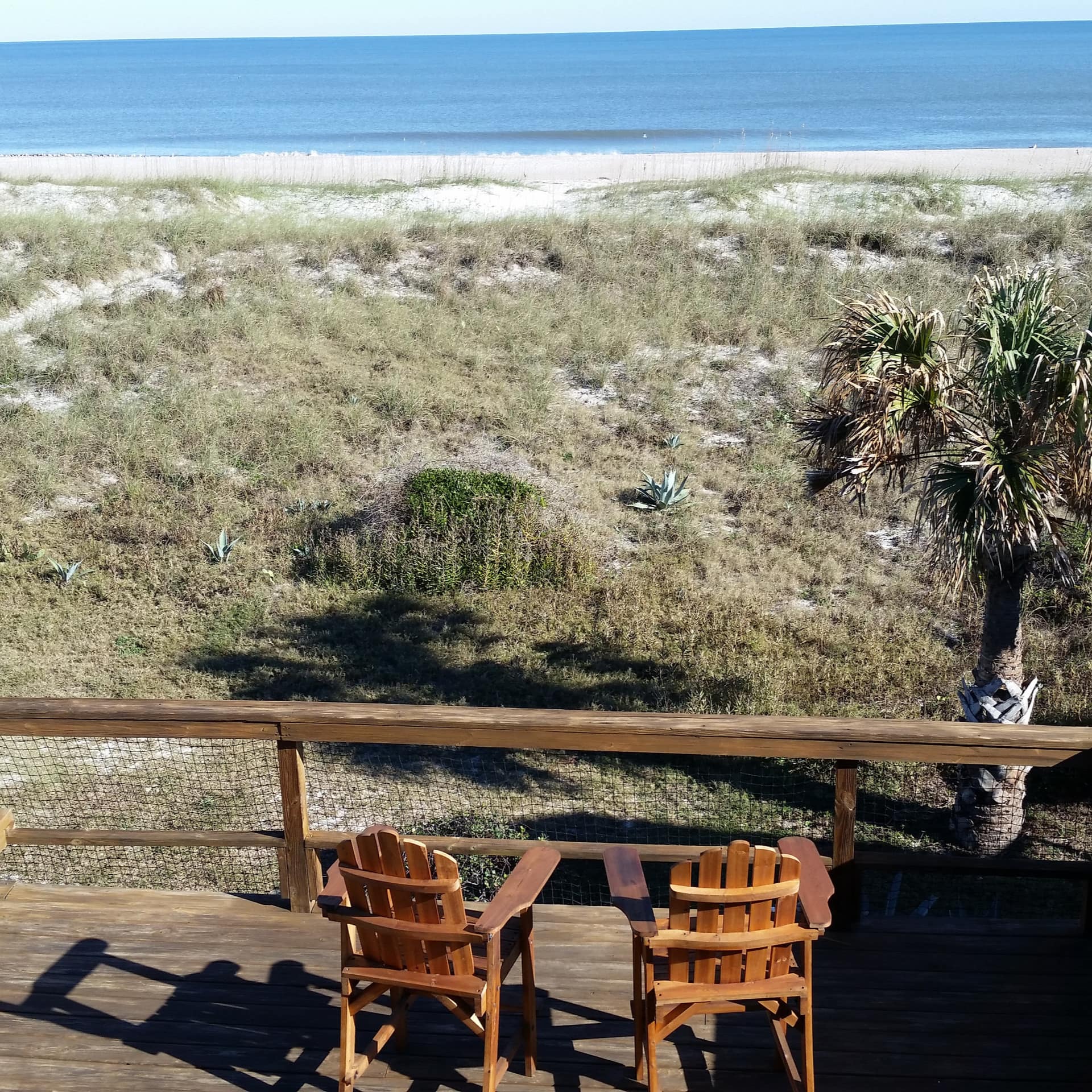 Two chairs sit on the deck of an oceanfront cottage in Florida
