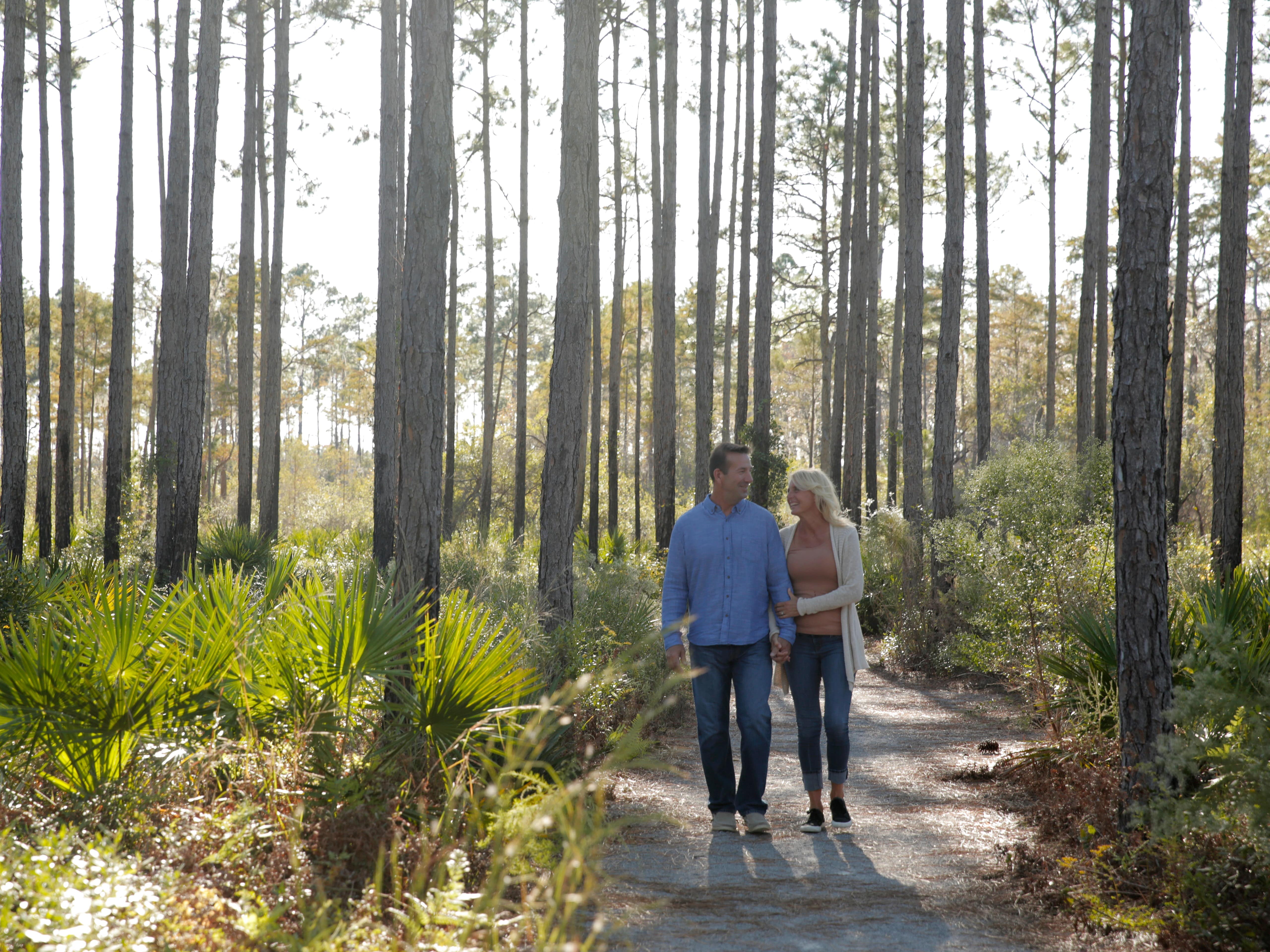 a couple walking arm in arm through the trees near panama city beach