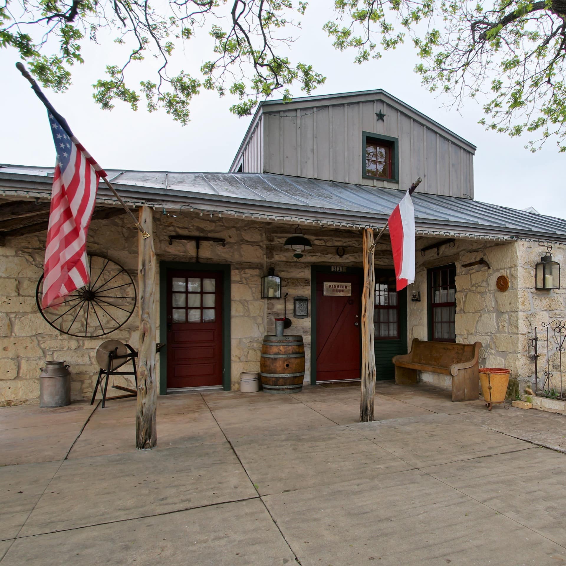 A guest house with a Texan ranch vibe has wagon wheels and barrels decorating its exterior